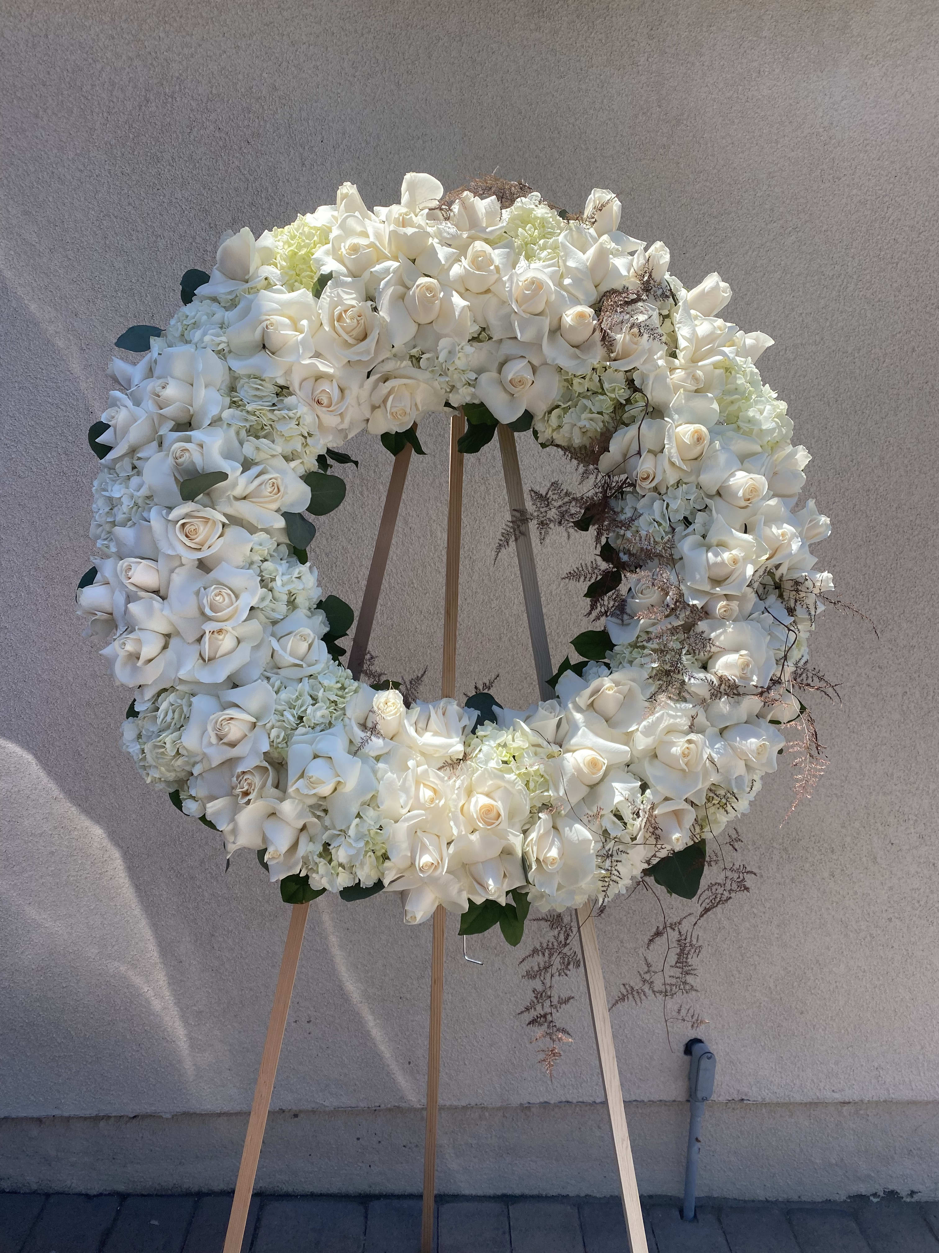 Large white floral wreath on a wooden easel