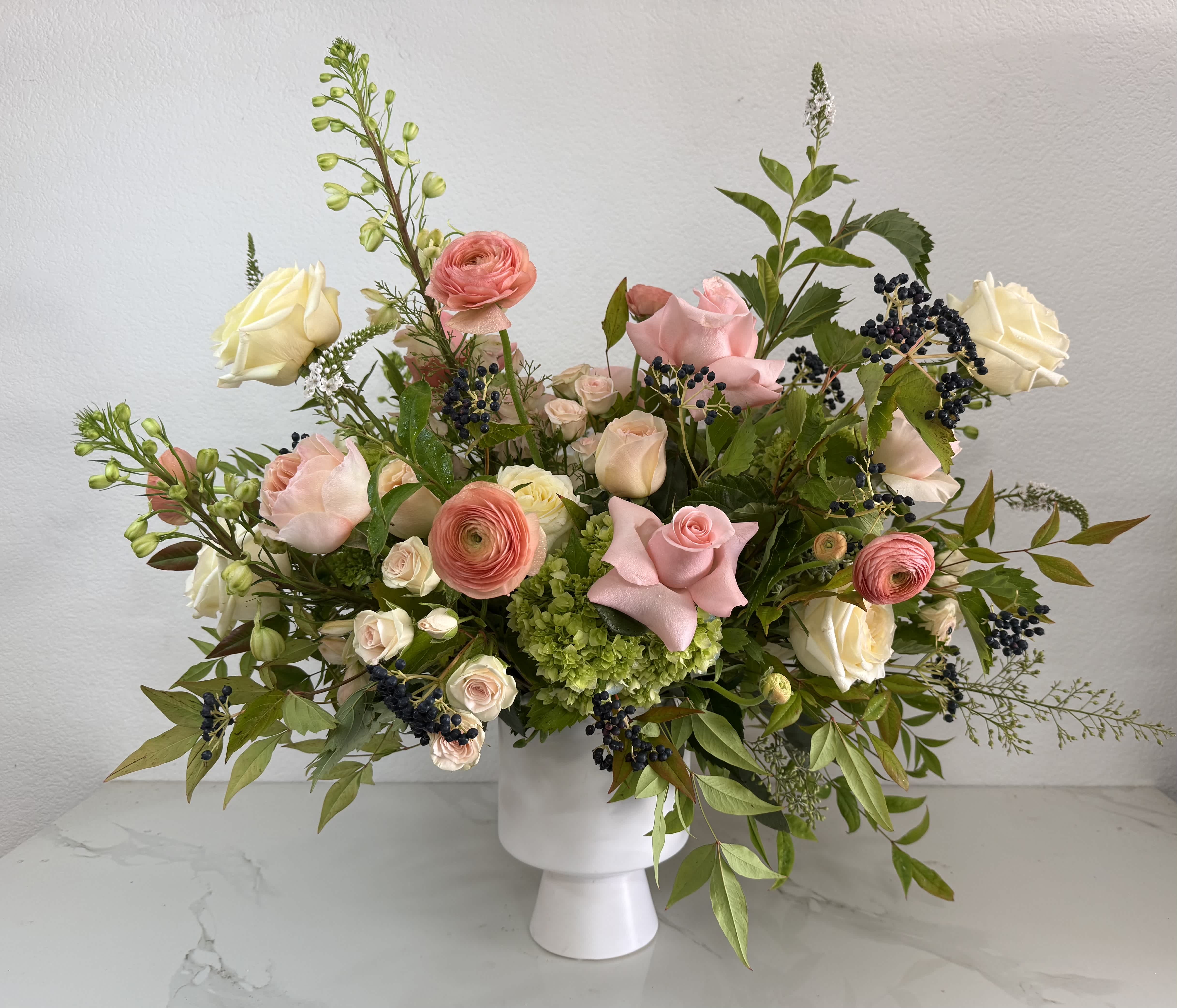 Pink and cream roses with ranunculus in a white vase