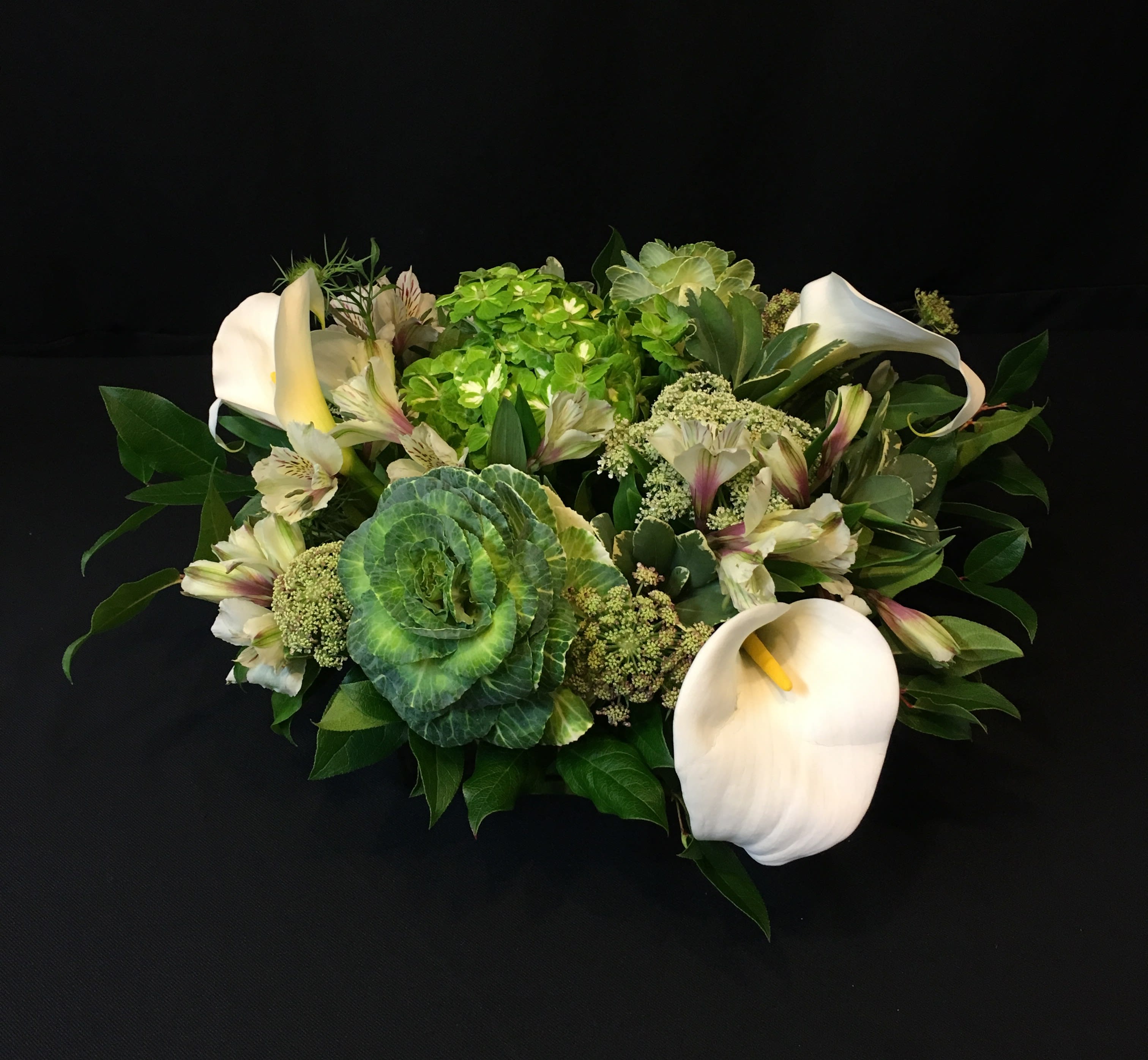 Pure White Modern Centerpiece in Rectangular Glass Vase - Keepsake vase is breathtaking all on its own but we have paired it with large impressive blooms. Seasonal selection will vary. Shown are calla lilies, cabbage, hydrangea, chocolate lace, and alstroemeria. 