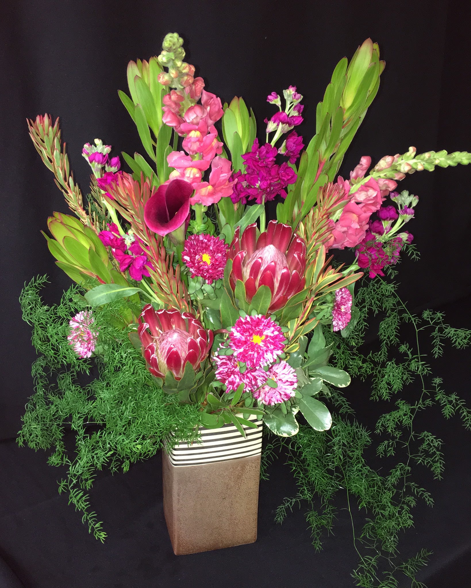 Tall floral arrangement with pink and magenta blooms in a rectangular vase