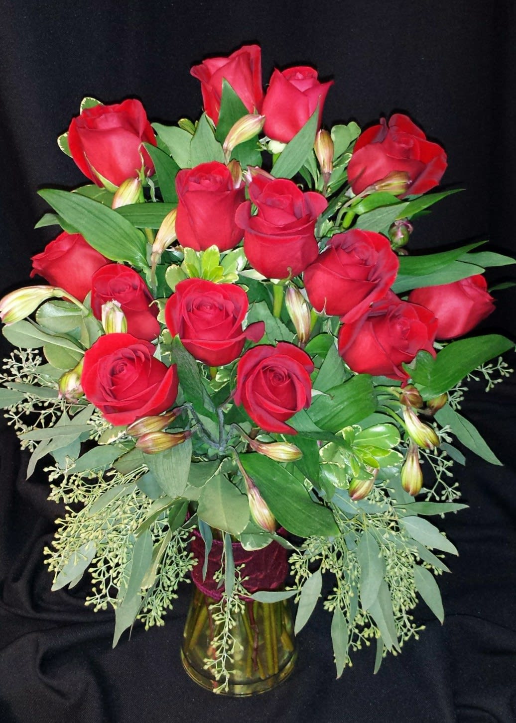 Dozen Medium Roses with Seeded Eucalyptus - Red or Colored  - Compare our premium medium stem roses to any other florist and you'll find ours are bigger, fresher and actually more affordable. Our medium dozen includes filler flowers, greenery, a ribbon clutch or bow, and quality vase. Rose color, Vase and accent flowers may vary.  Red Dozen unless  1) Red is unavailable  This happens at times, especially when less than 1 week advance notice (3 week notice Valentine's day) is given on your order &amp; we will notify you if this is the case or  2) You Choose Colored.  (Write Colored Roses in the Special Requests section. We cannot guarantee a specific color with online orders)  Includes filler flowers, greenery and vase. We deliver our roses completely arranged so there is no fuss to find scissors. All of this is included; there are no hidden costs for the best, most perfect roses you will find.