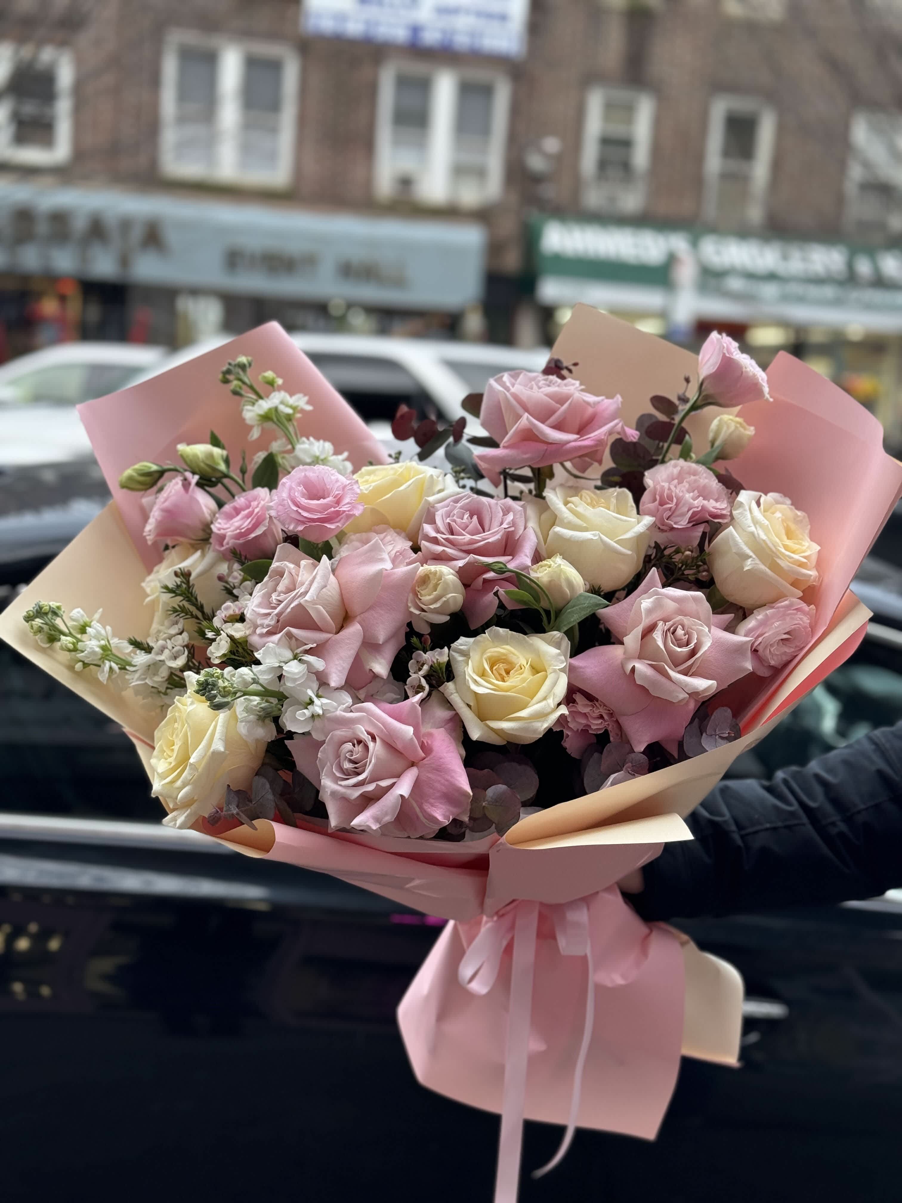 Bouquet of pink and cream roses wrapped in pastel paper