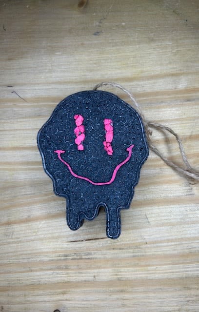 Black skull-shaped hanging ornament with a pink smiley face