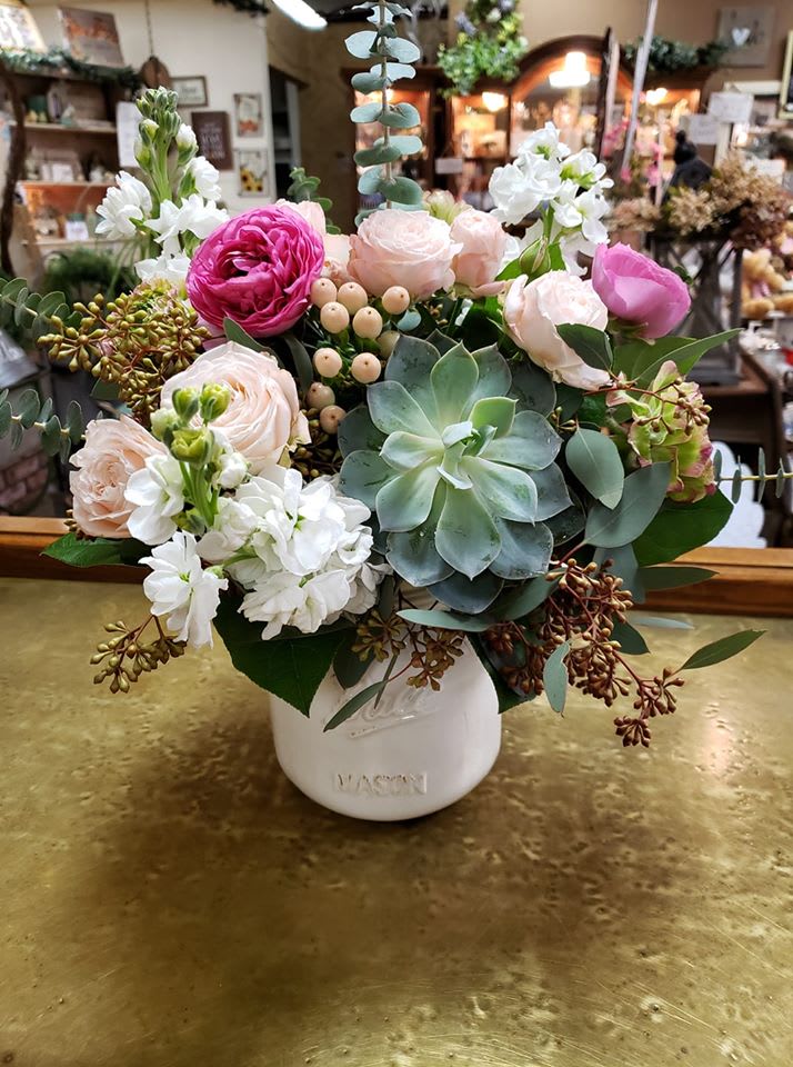 Mixed pink and white flowers in a white vase with succulents