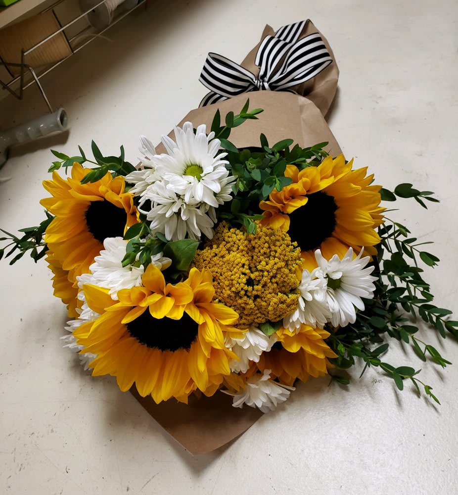 Bouquet of sunflowers, white daisies, and yellow filler flowers wrapped in brown paper
