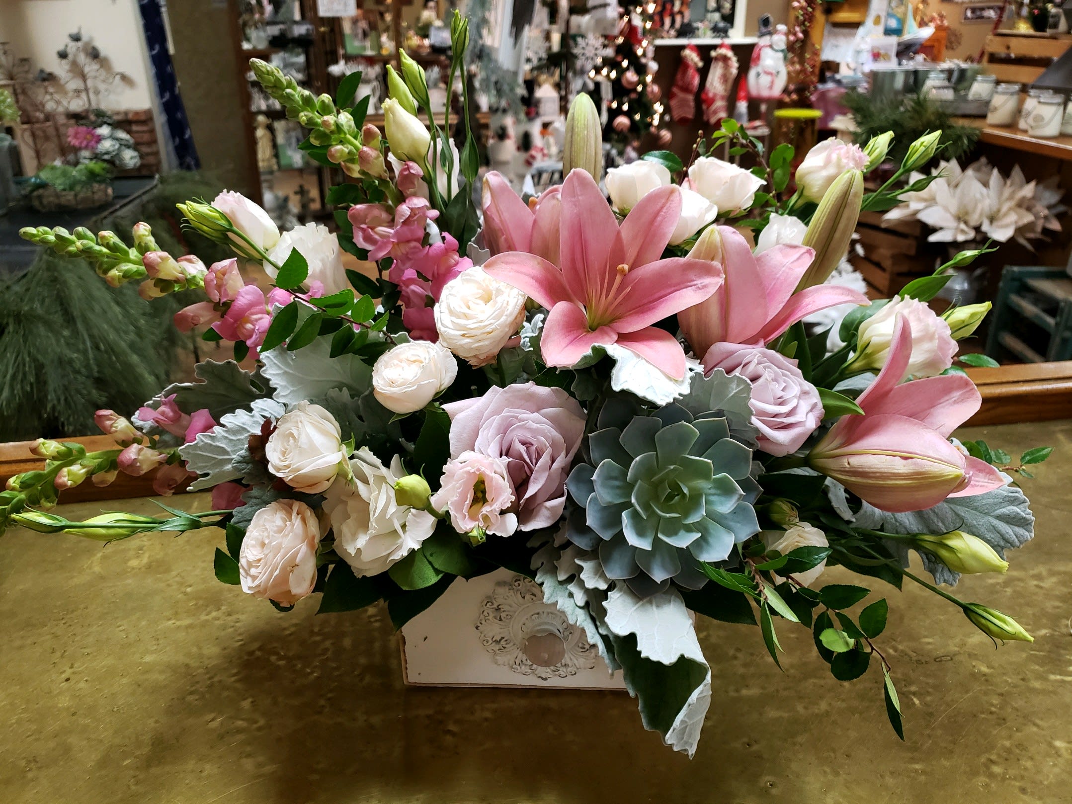 Pink lilies and pale roses arranged in a decorative box
