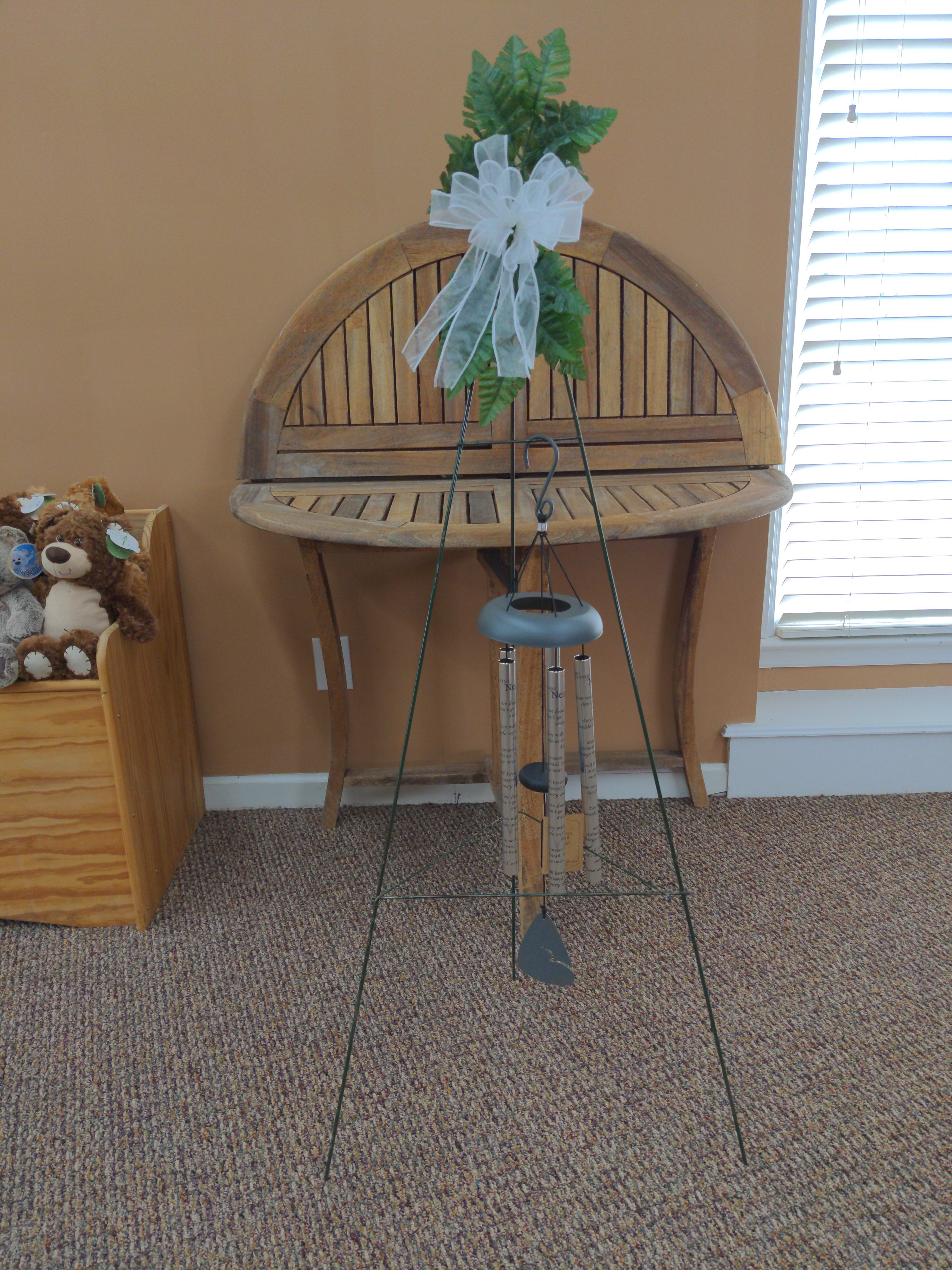 Greenery tied with a white bow on a metal wind chime stand