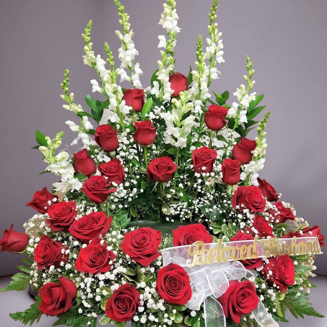 Red roses with white snapdragons and baby's breath in a large arrangement.