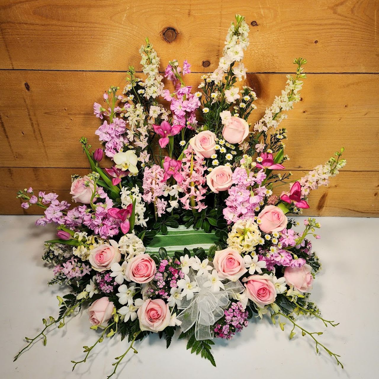 Pink and white floral arrangement with roses and orchids in a fan shape