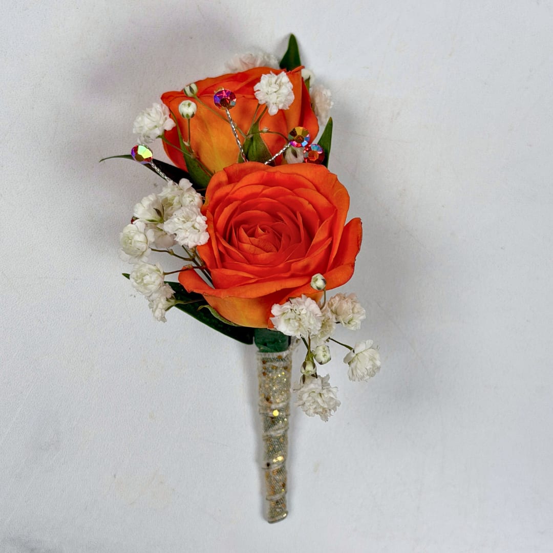 Citrine Boutonniere - With Wrap and Sparkle - Two vivid orange rose blooms make this boutonniere a bright, celebratory accent for prom or any special-event lapel. The orange-and-white palette (roses with tiny white baby's breath) creates an energetic yet refined look that will make the person you're thinking of feel noticed and adored.  This version of this design is the most spectacular of them all, with a shimmering white and gold ribbon wrap creating a subtle but classy touch to this boutonniere, and a stem of orange rhinestone sparkle accents is the final dazzling touch to make your night even more special. A boutonniere pin is included so it sits neatly on a suit or jacket without any fuss so you can spend your evening dancing the night away.  If you want to change the color of either the ribbon wrap or the sparkle accents, check out our add-ons below or at checkout and pick your desired color.