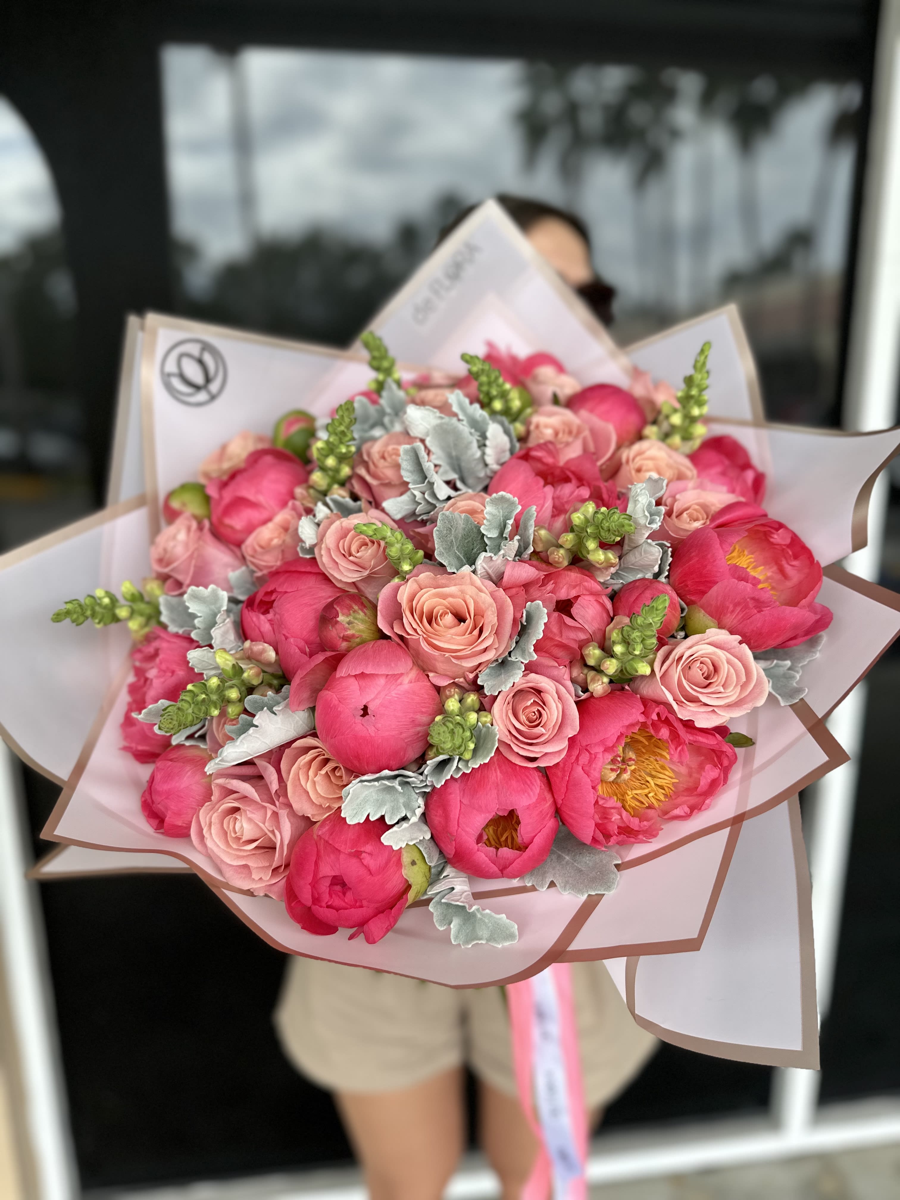 Bouquet of pink peonies and blush roses wrapped in pale paper