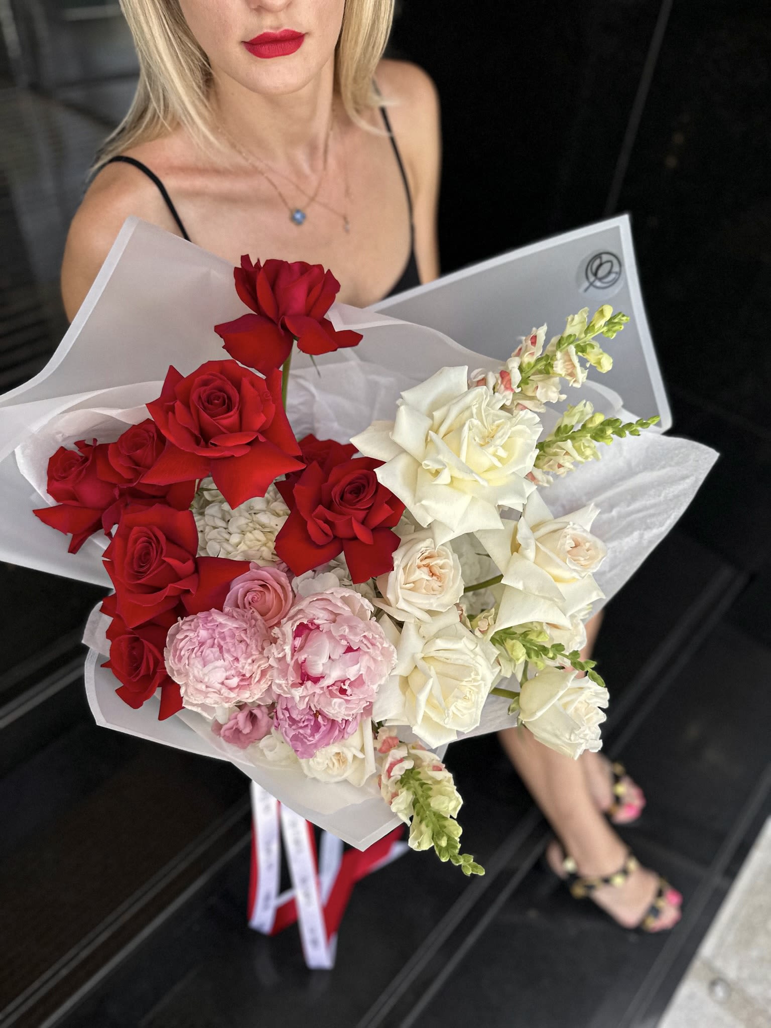 Bouquet of red, white, and pink roses wrapped in white paper