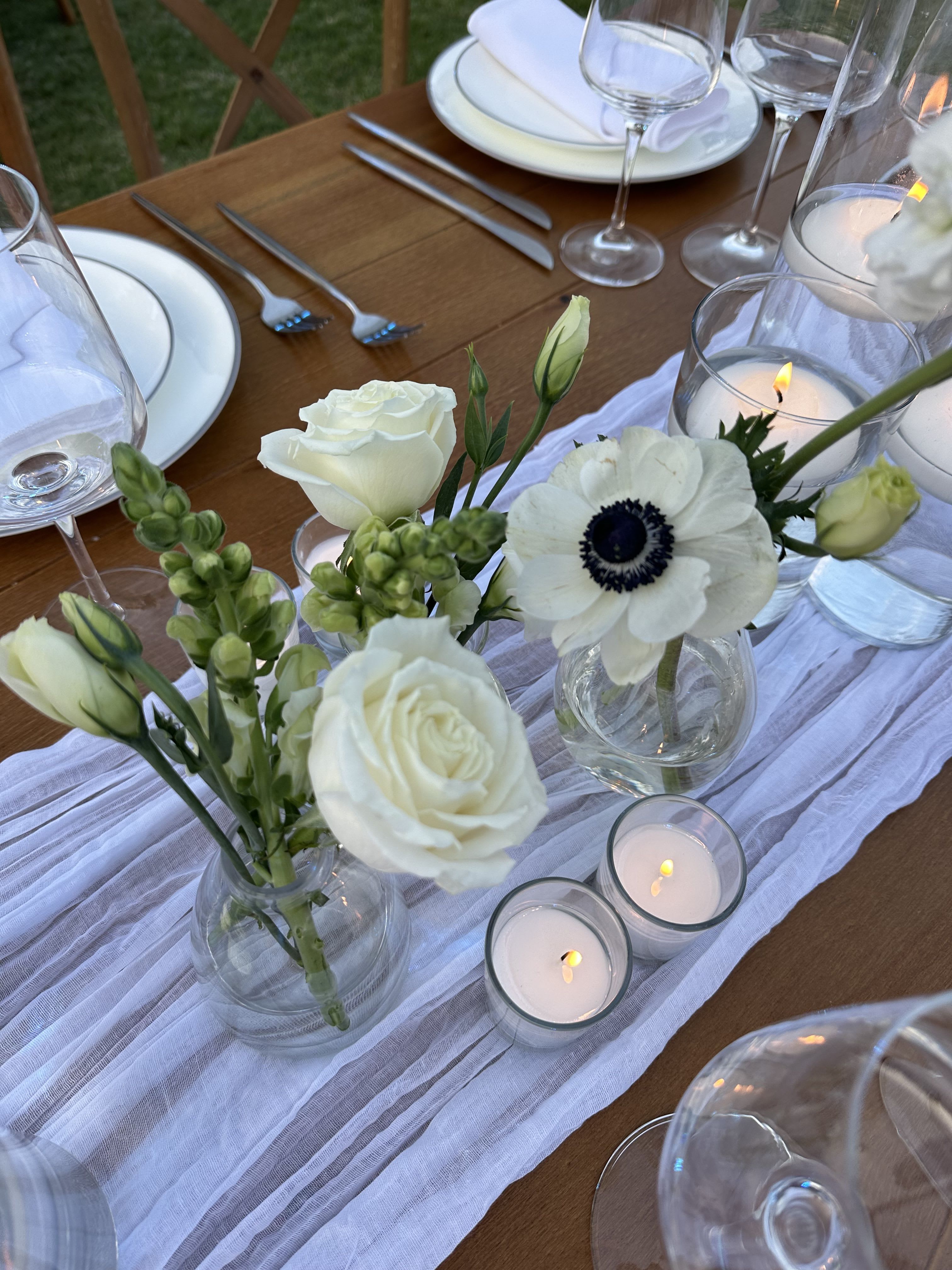 White floral centerpieces with candles on a set dining table