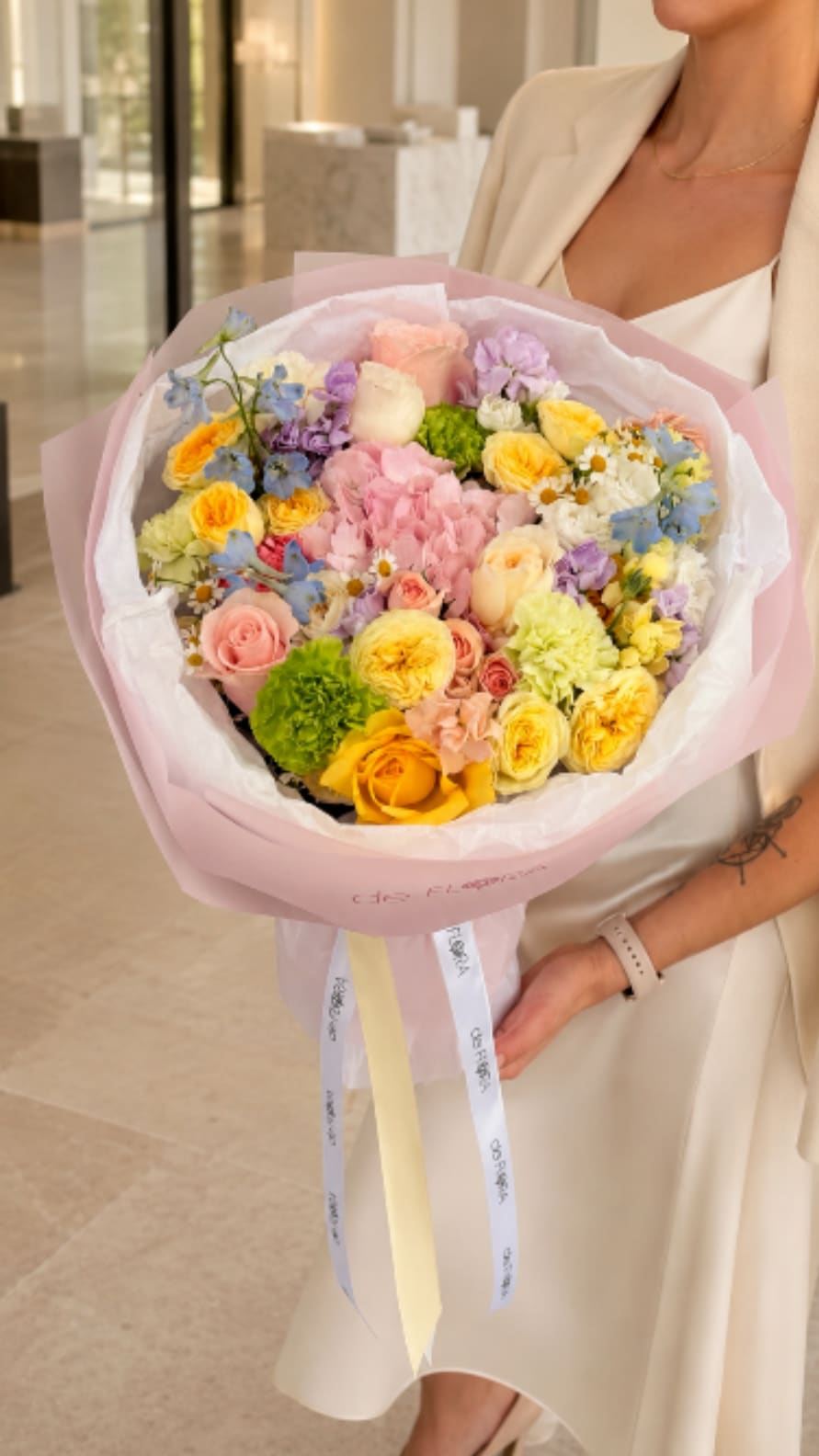 Pastel mixed bouquet with roses, carnations, and daisies wrapped in pink paper