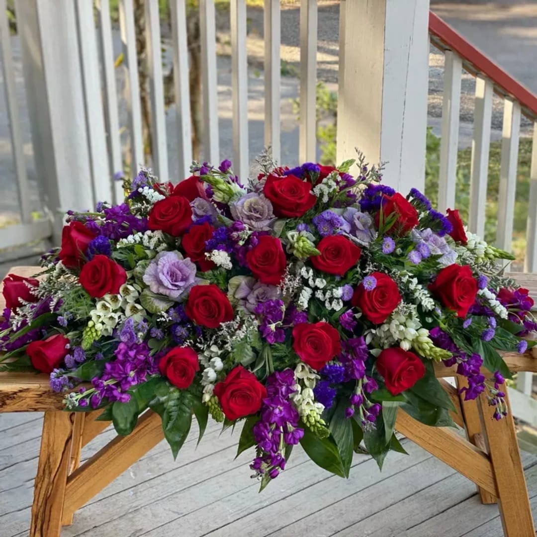 Large arrangement of red roses and purple flowers on a wooden table