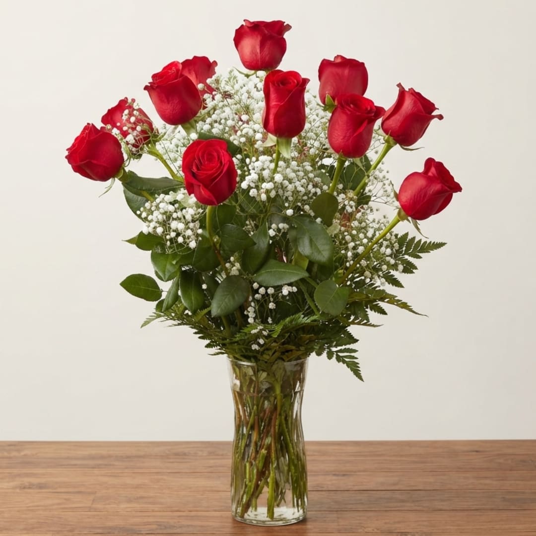 Red roses arranged in a clear glass vase with white baby's breath