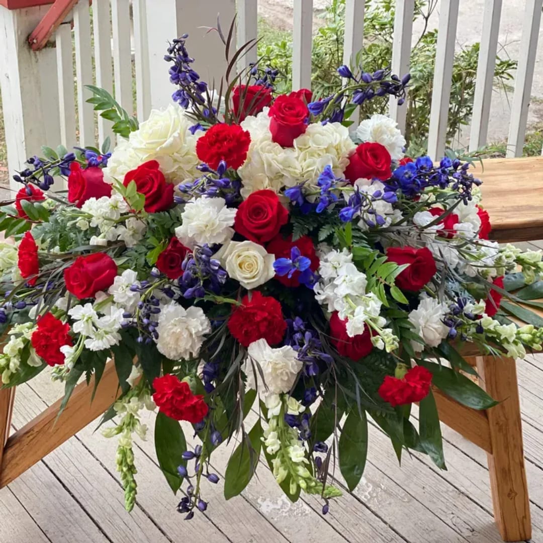 Large red, white, and blue floral arrangement on a wooden table