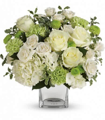 White roses and green carnations in a clear square vase