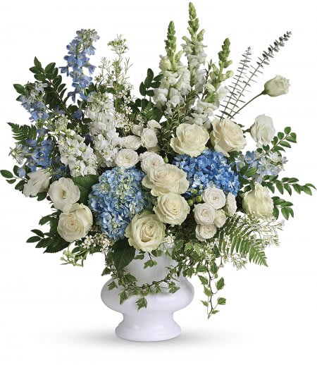 White and blue floral arrangement in a white pedestal vase