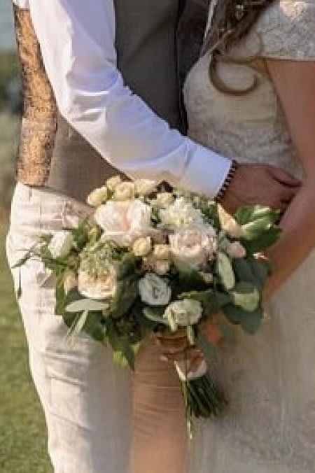 Bride and groom holding a small white and blush bouquet