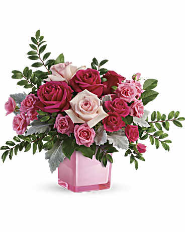 Pink and white roses arranged in a pink glass vase