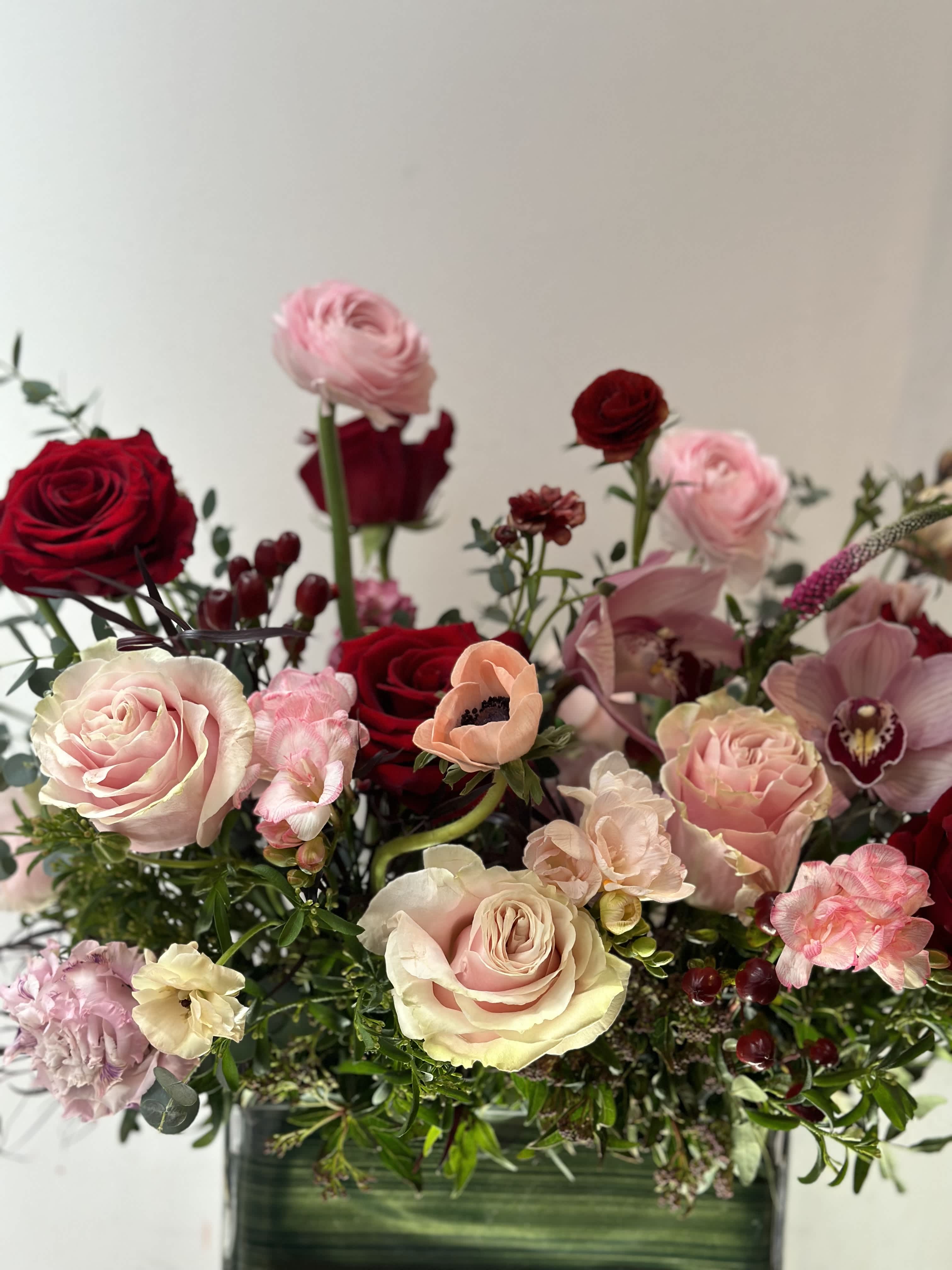 Mixed bouquet of roses and pink blooms in a green vase