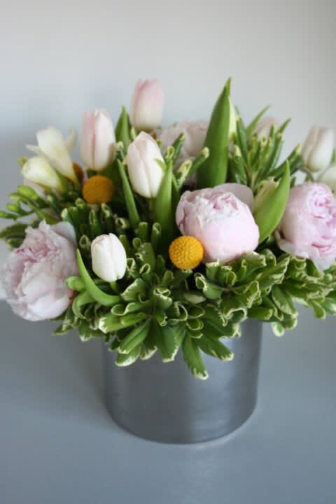 Pink and white tulips with pale peonies in a gray vase