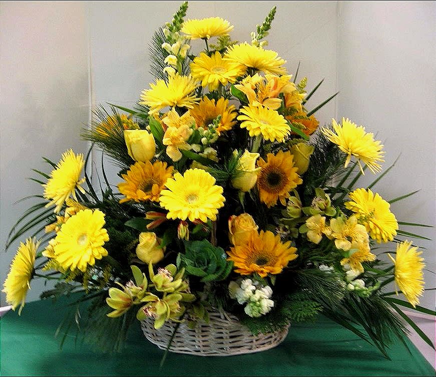 Yellow and orange mixed flower arrangement in a white basket