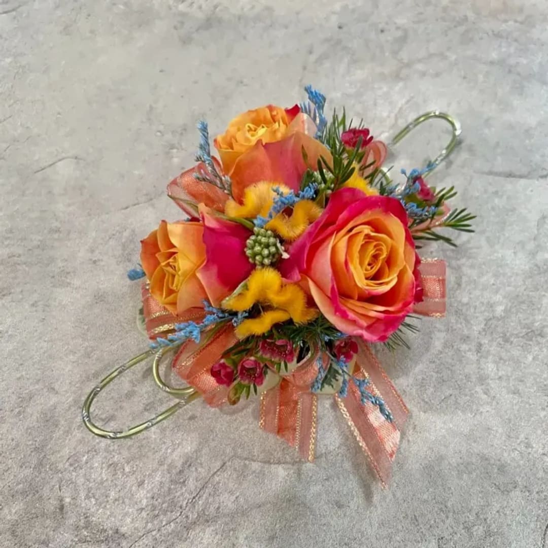 Small colorful floral corsage with roses and ribbon on a gray surface