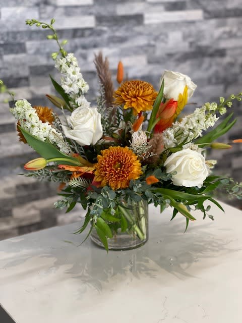 Mixed bouquet of white roses and orange chrysanthemums in a glass vase