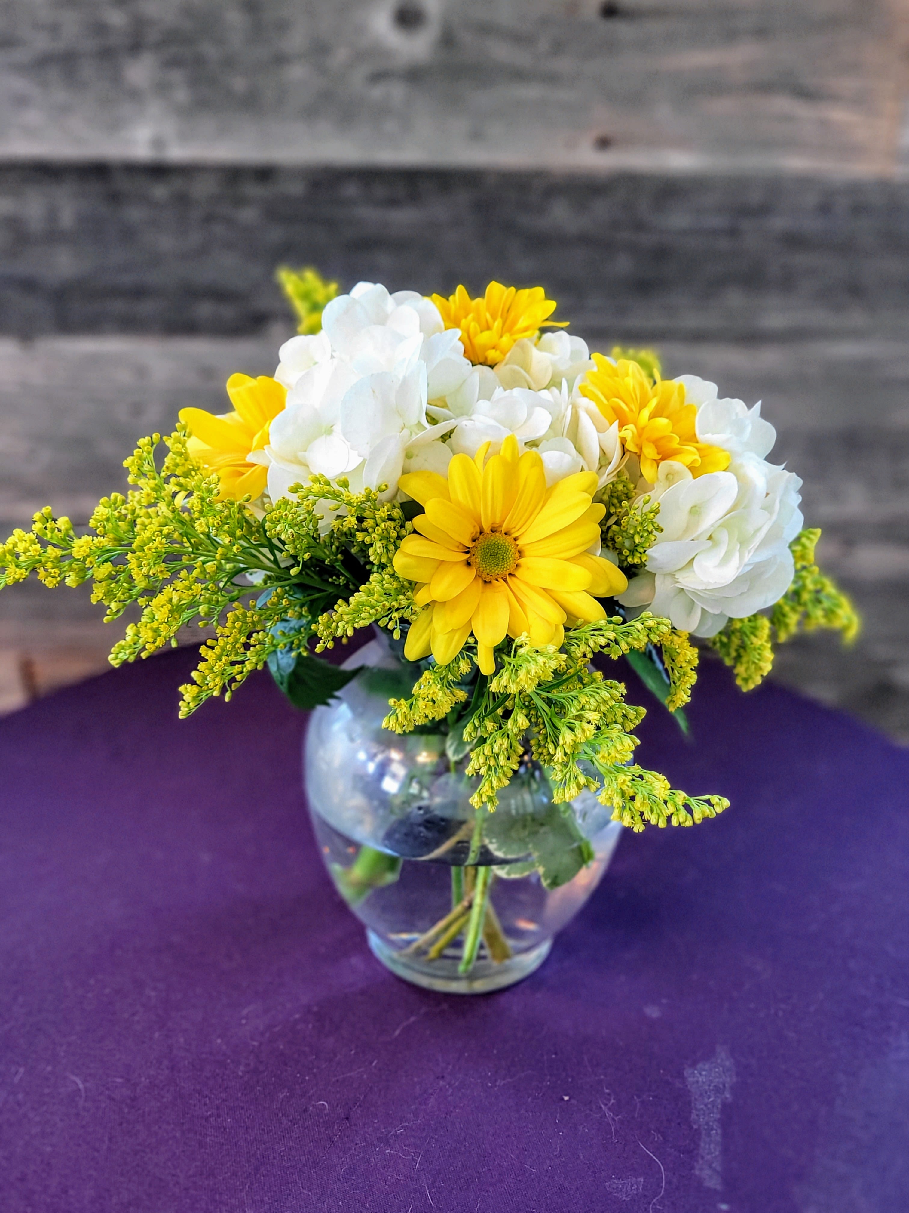 Yellow and white flowers arranged in a clear glass vase