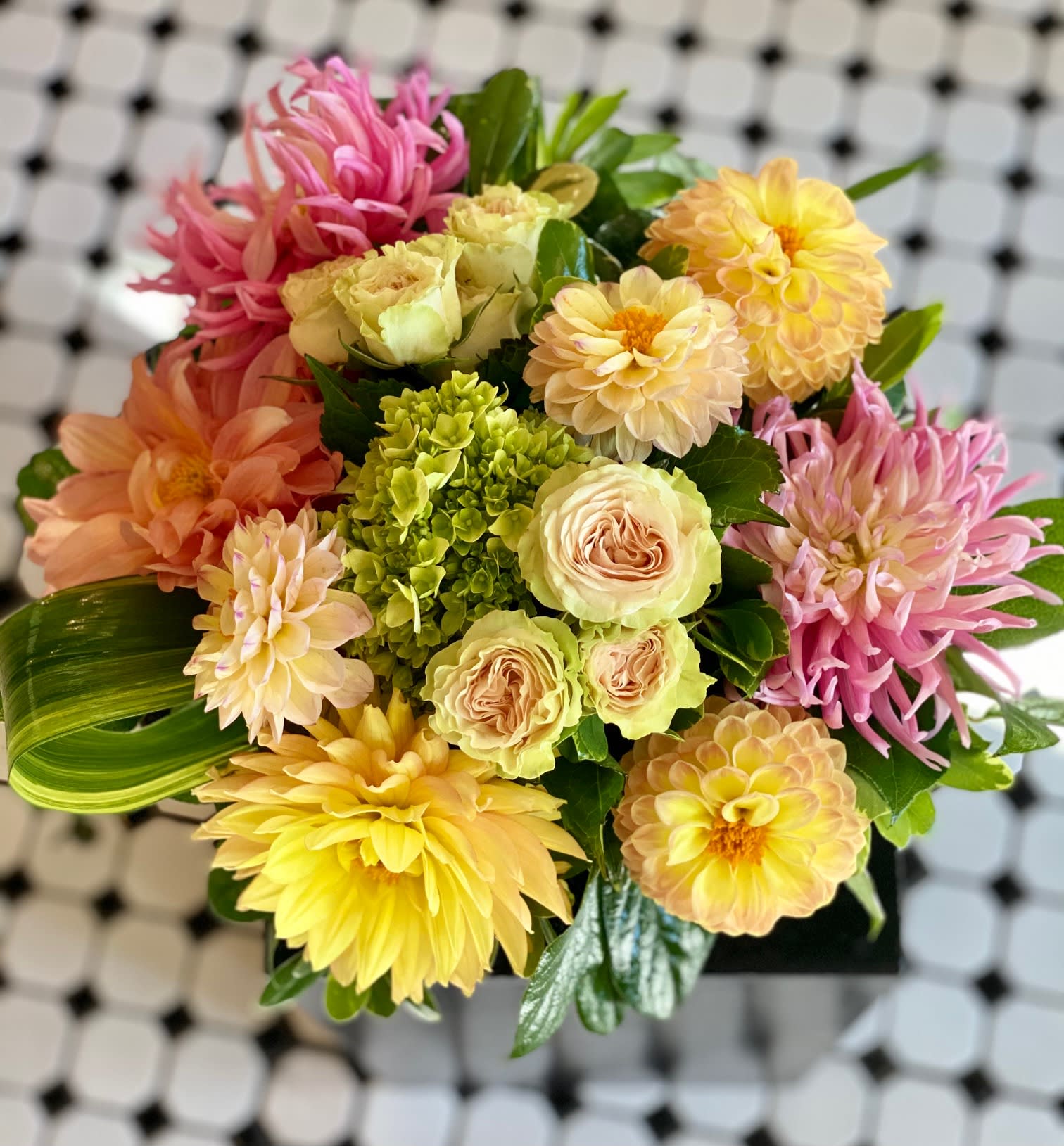 Mixed bouquet of pink, yellow, and peach flowers in a compact arrangement