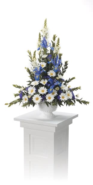 Tall blue and white floral arrangement in a white urn on a pedestal
