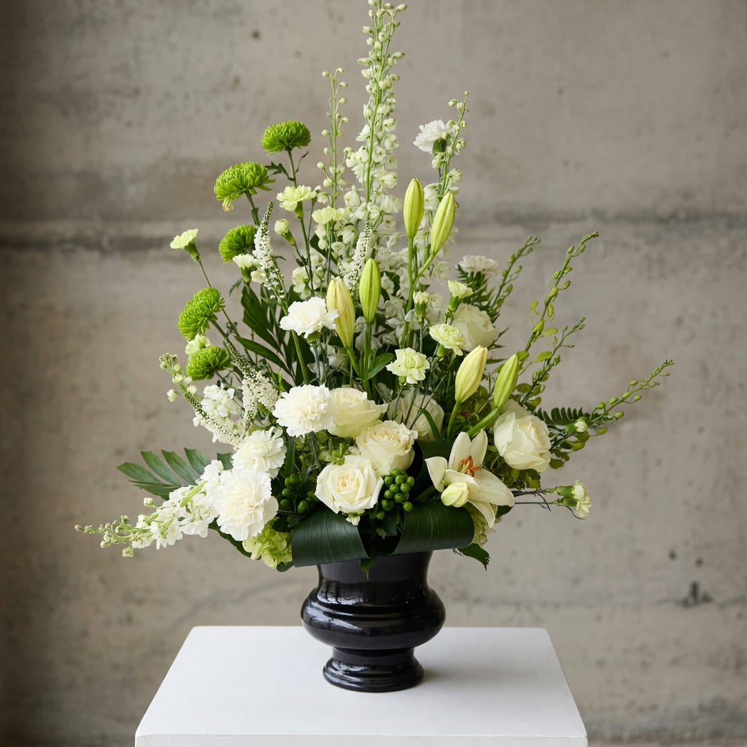 White and green floral arrangement in a black vase