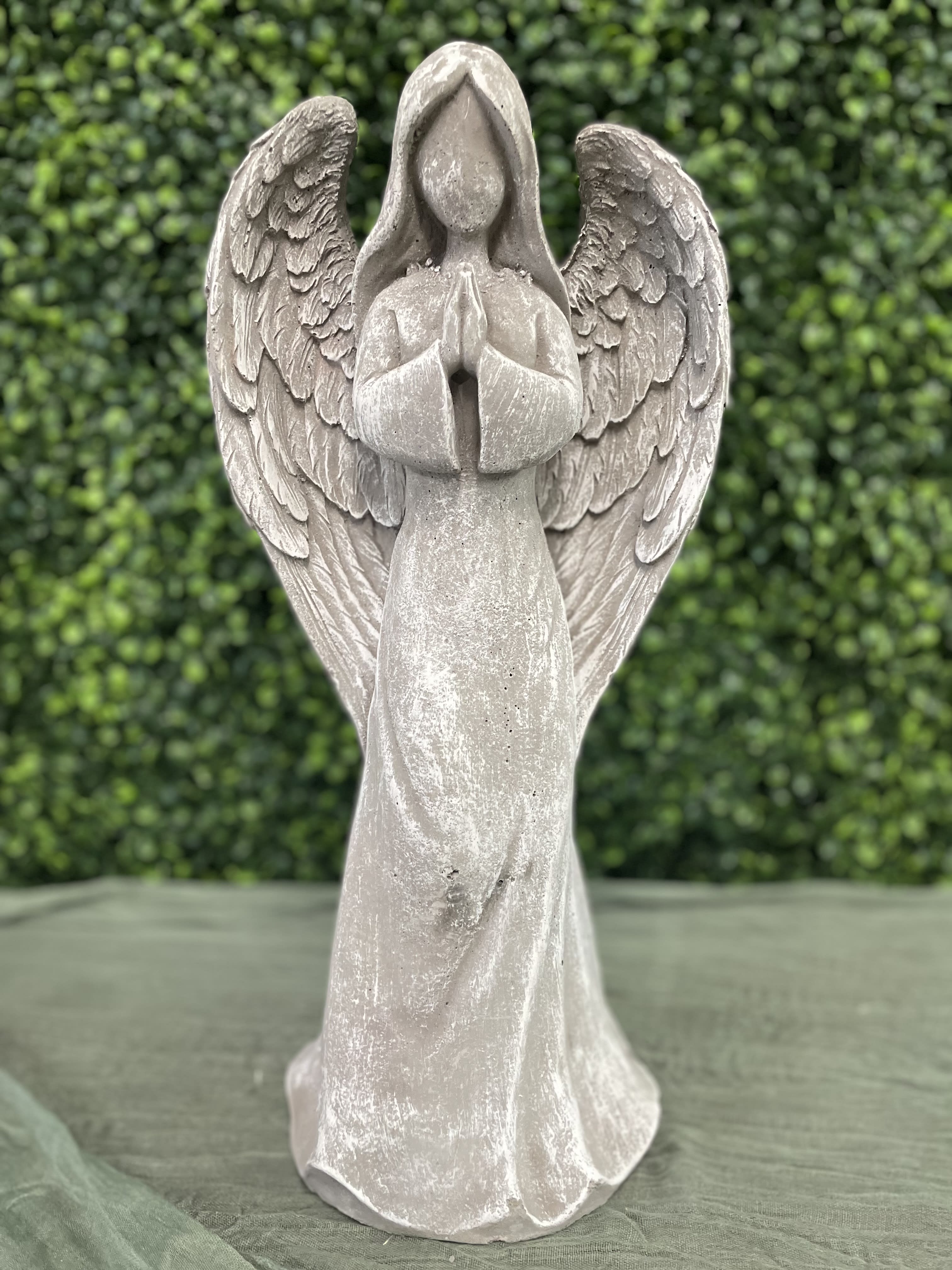 Stone angel figurine with folded hands and wings