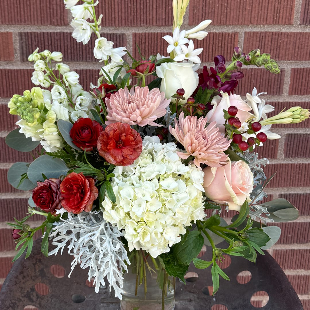 Mixed bouquet of roses, hydrangea, and chrysanthemums in a clear vase