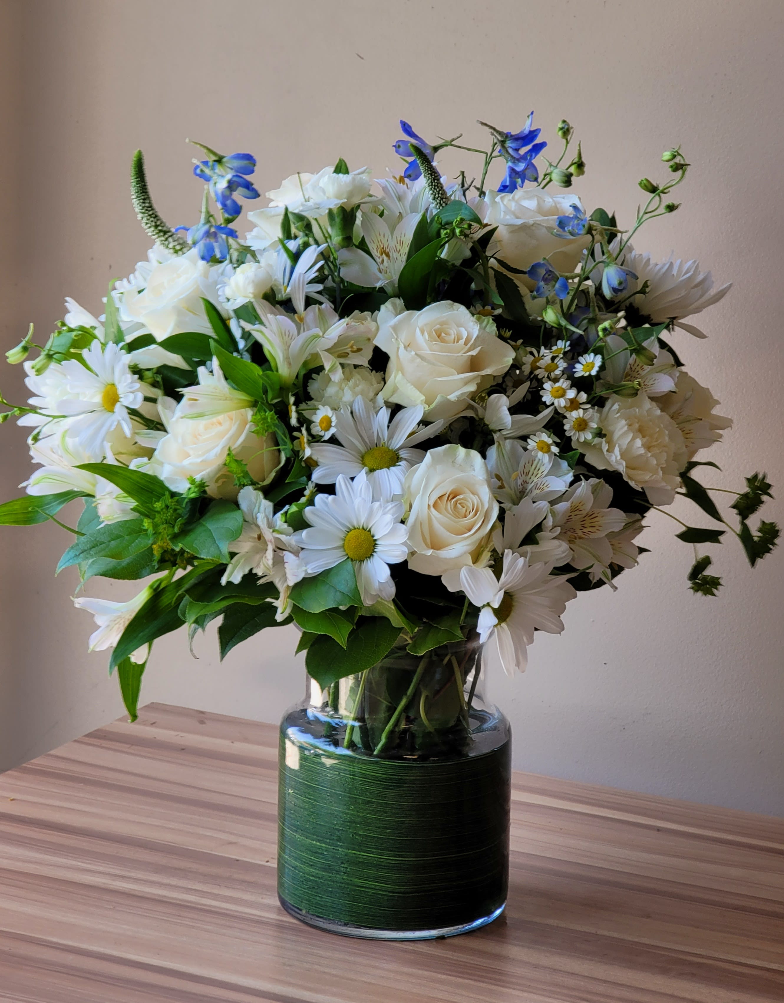 White and blue mixed flower bouquet in a glass vase