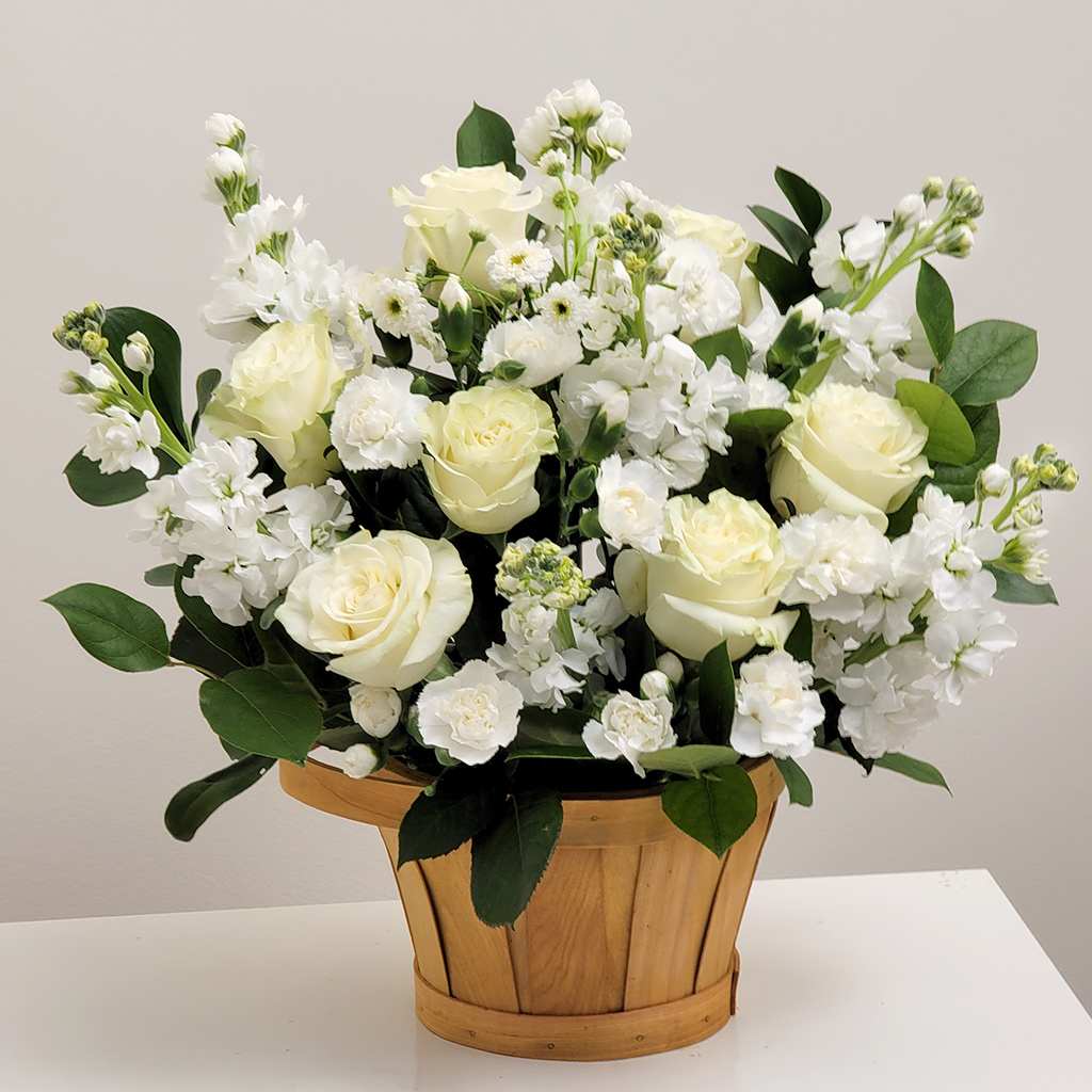 White roses and small white flowers in a wooden basket