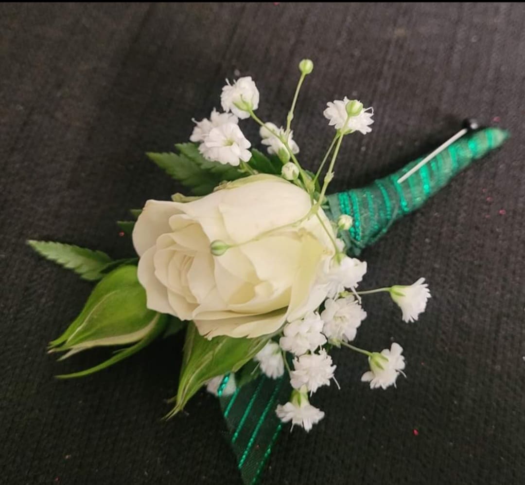 White rose boutonniere with baby's breath and green ribbon wrap