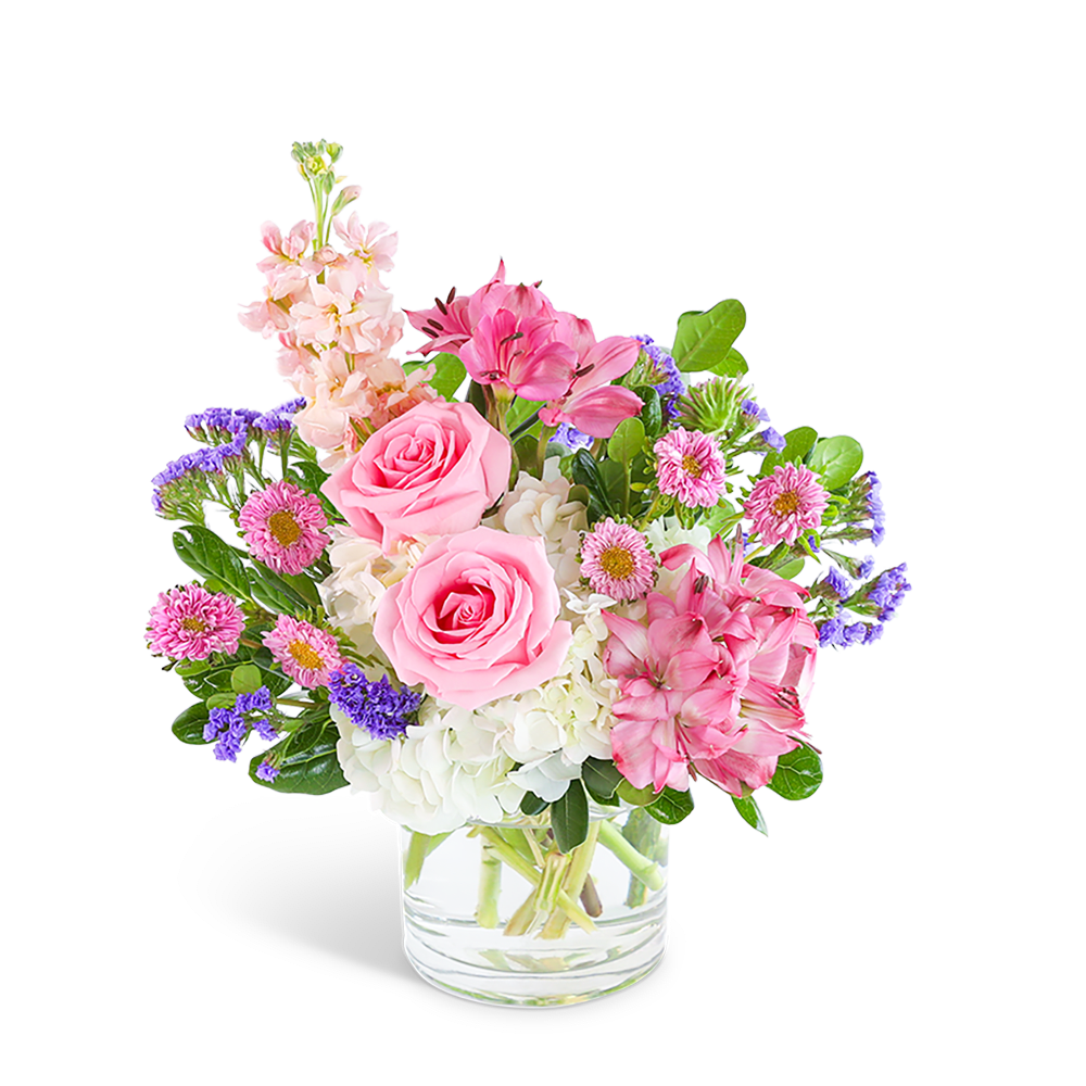 Pink roses and mixed flowers arranged in a clear glass vase