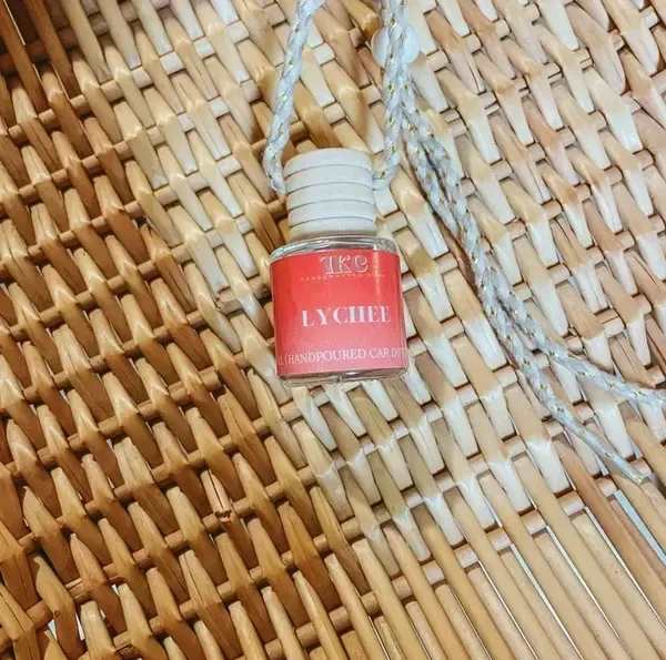 Small lychee-scented hanging candle bottle on a woven surface
