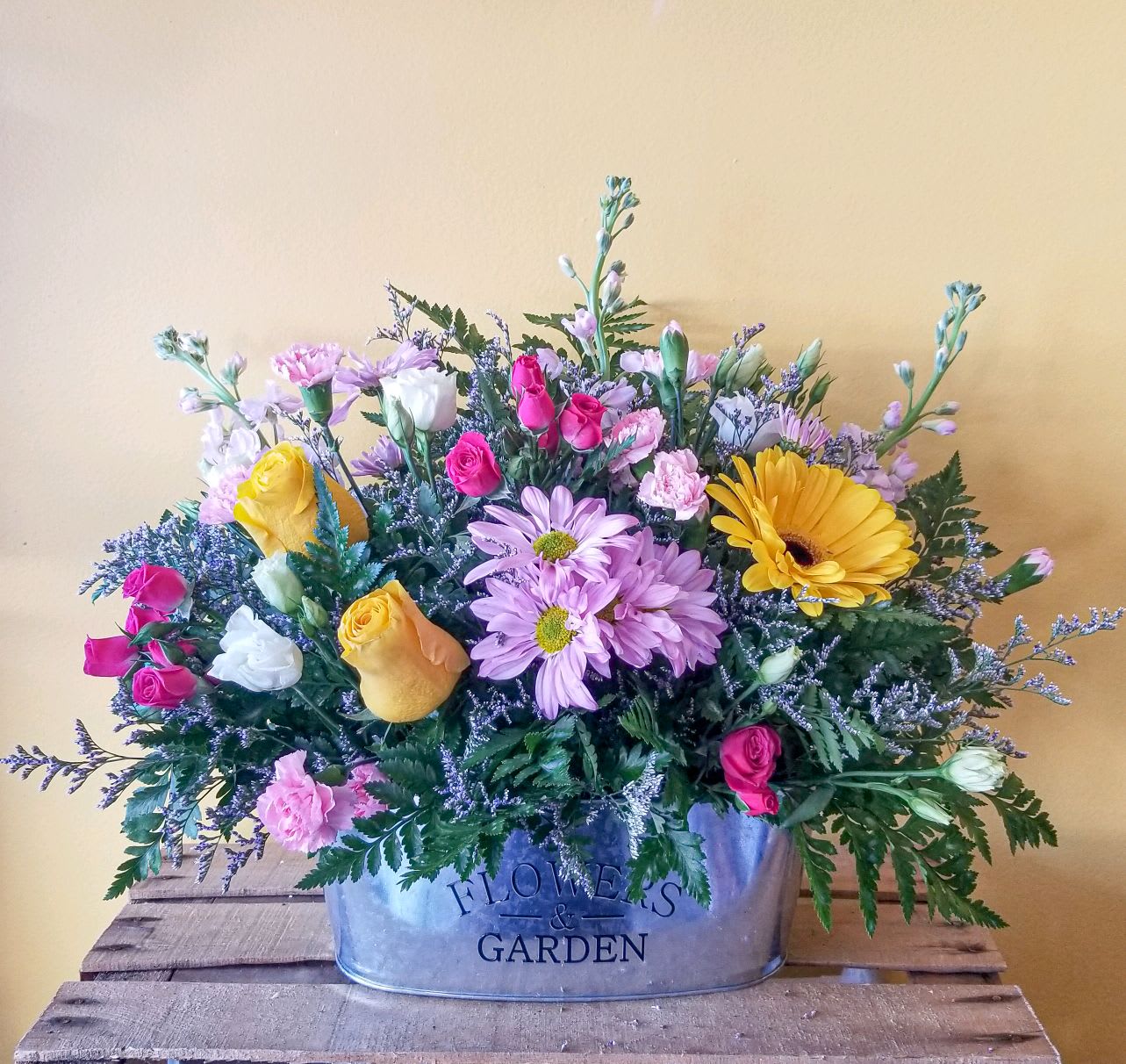 Mixed bouquet in a metal container with pink, yellow, white, and lavender flowers
