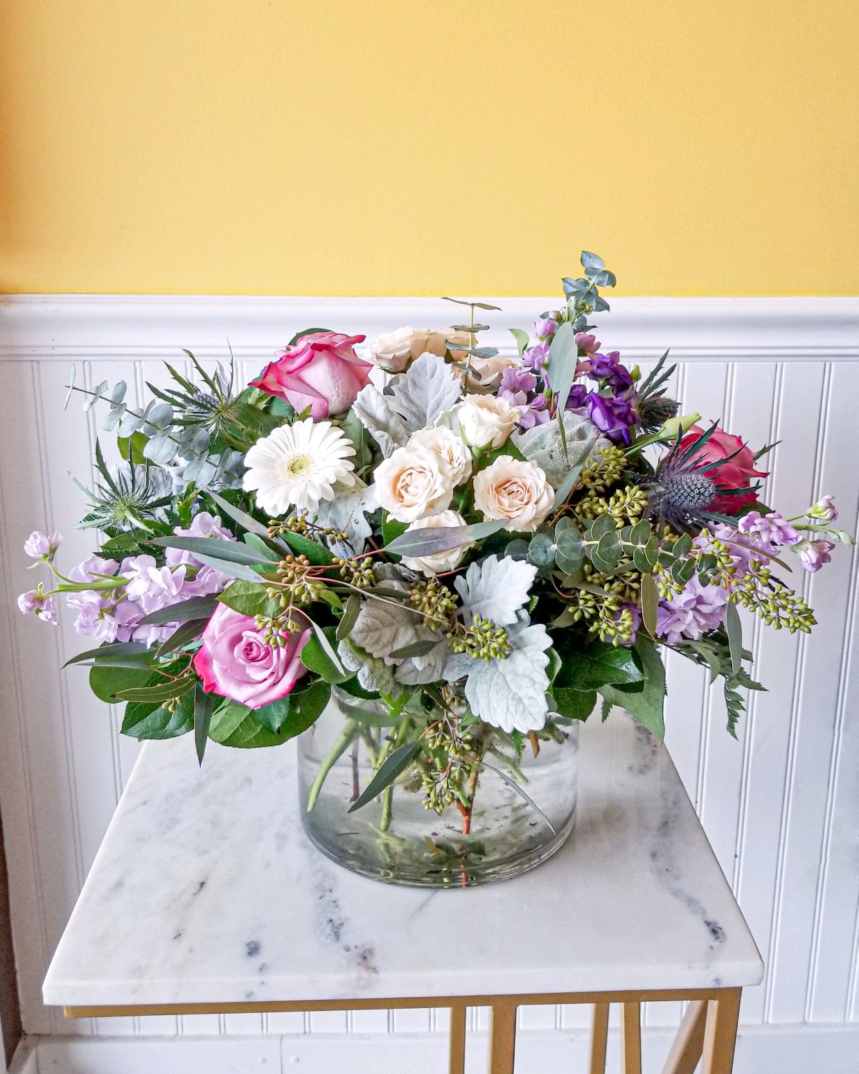Mixed bouquet of pink, white, and lavender flowers in a glass vase
