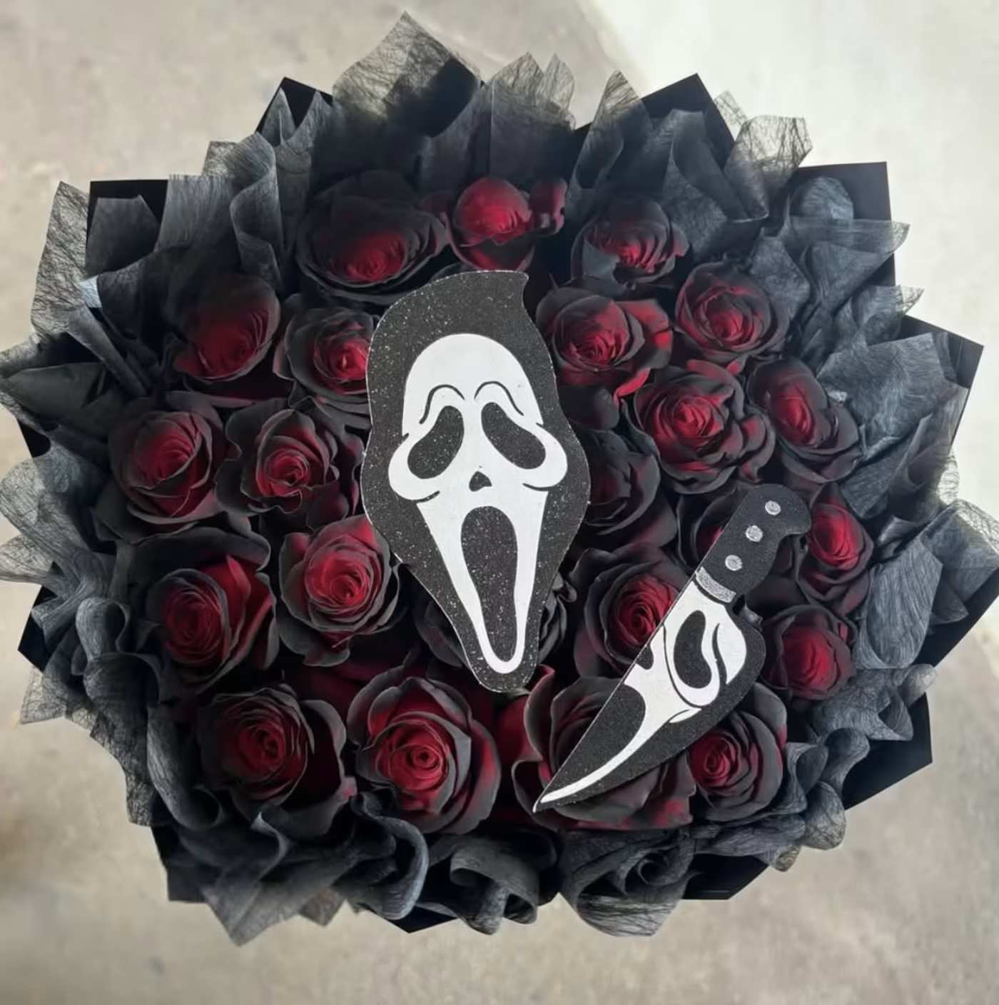 Bouquet of dark red roses with black wrapping and horror-movie face cutouts