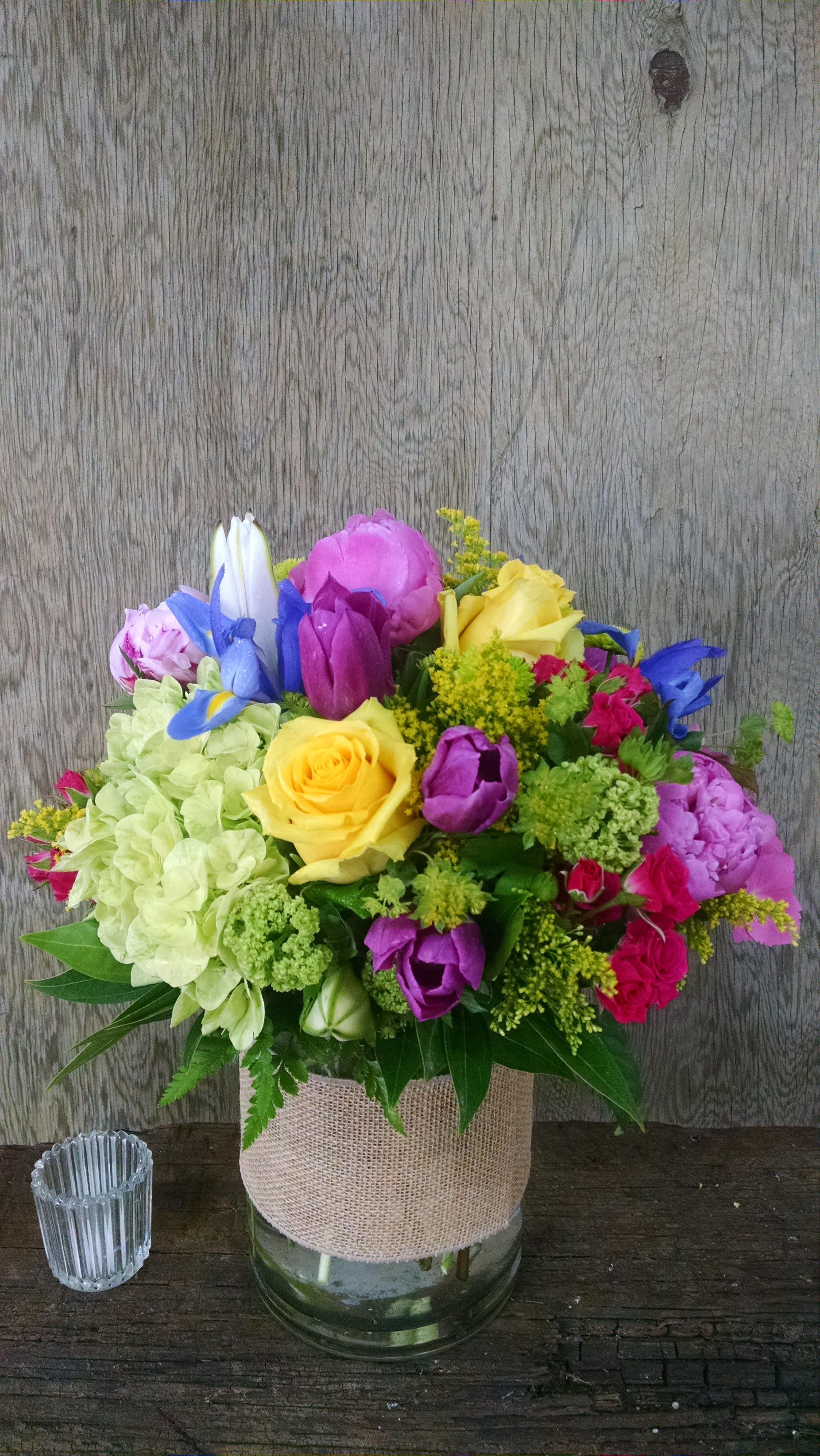Colorful bouquet in a glass vase wrapped with burlap