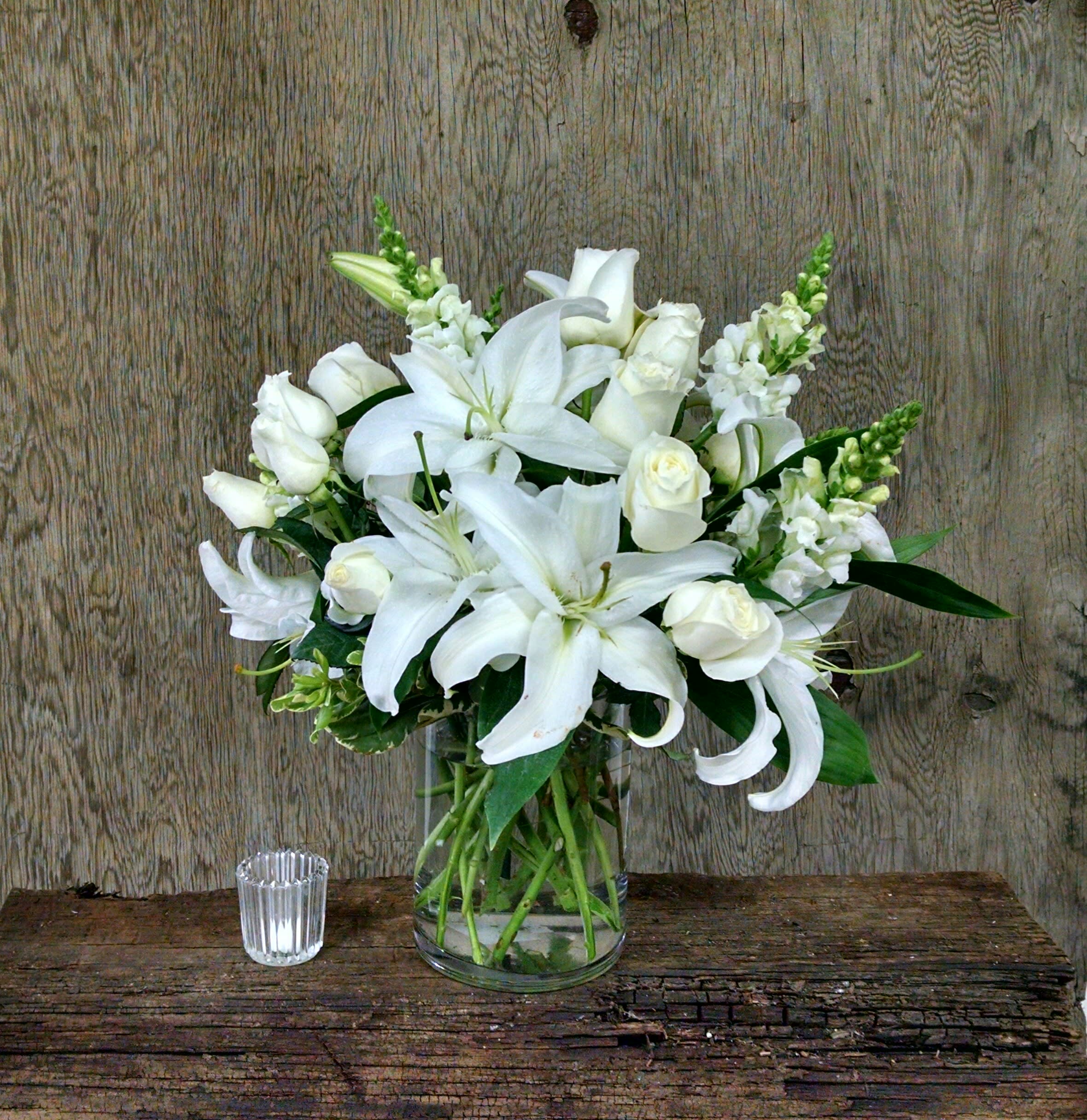 White lilies and roses arranged in a clear glass vase