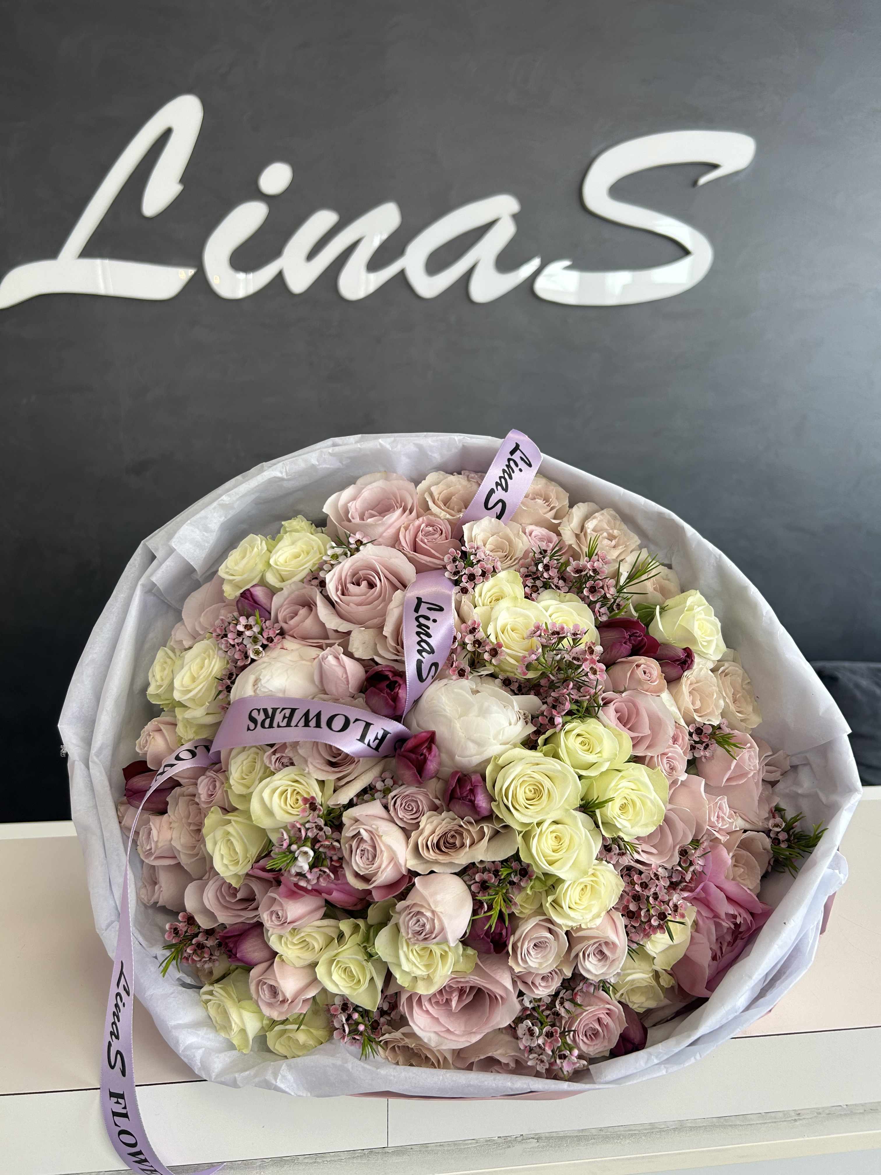 Large bouquet of pale pink and cream roses wrapped in white paper