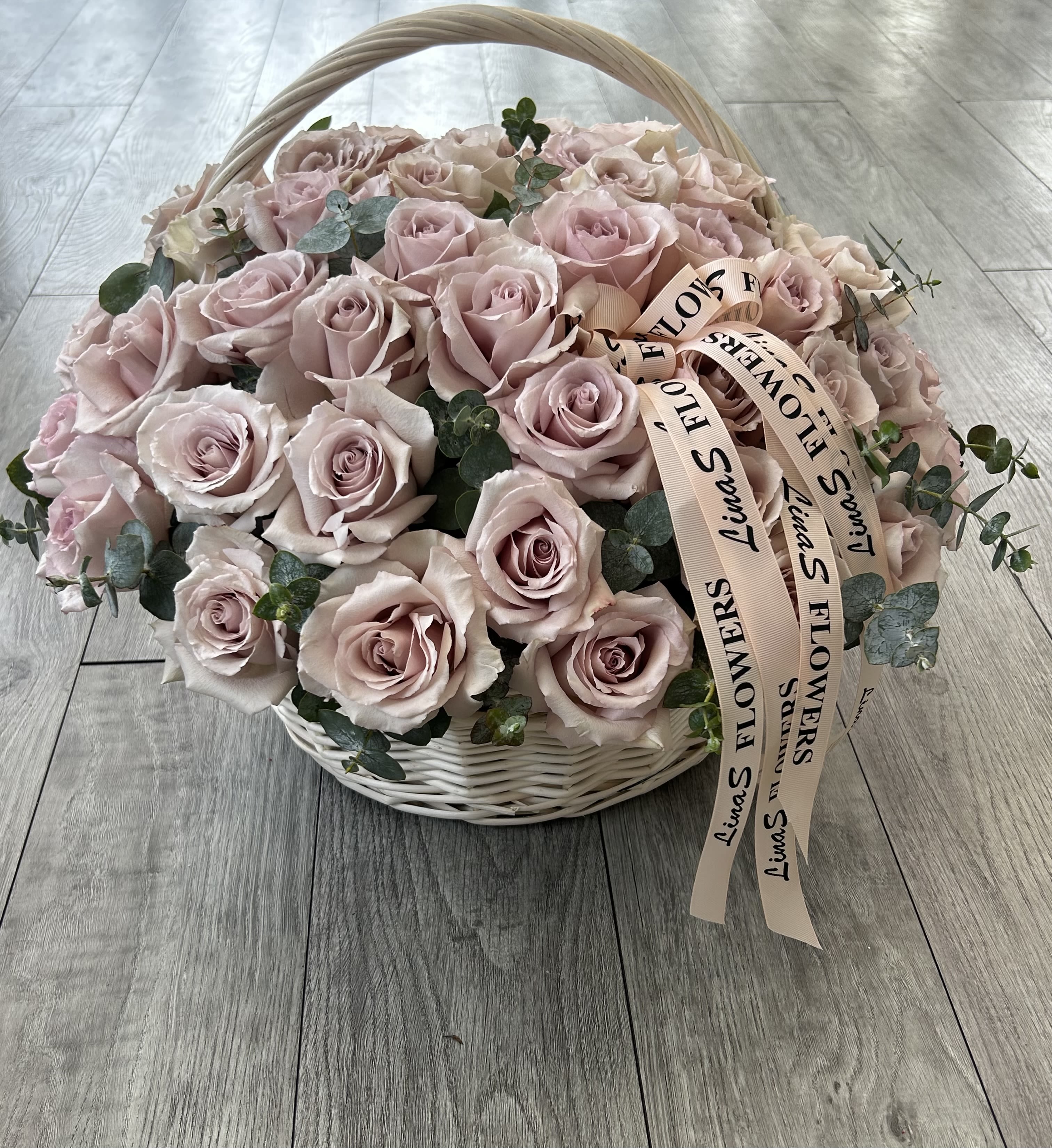 Basket of pale pink roses with eucalyptus and ribbon