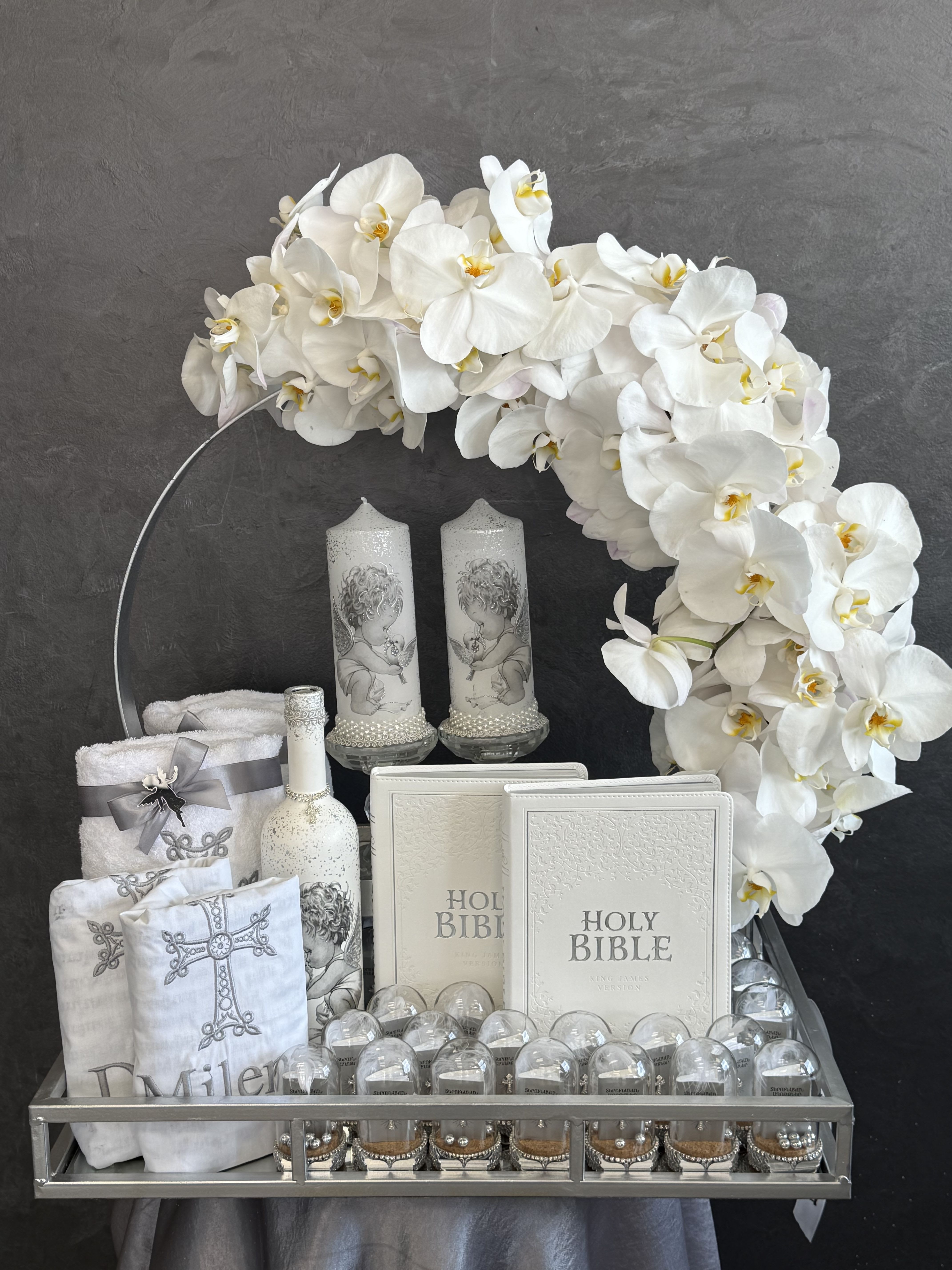 White orchid arrangement with candles, Holy Bibles, and religious keepsakes