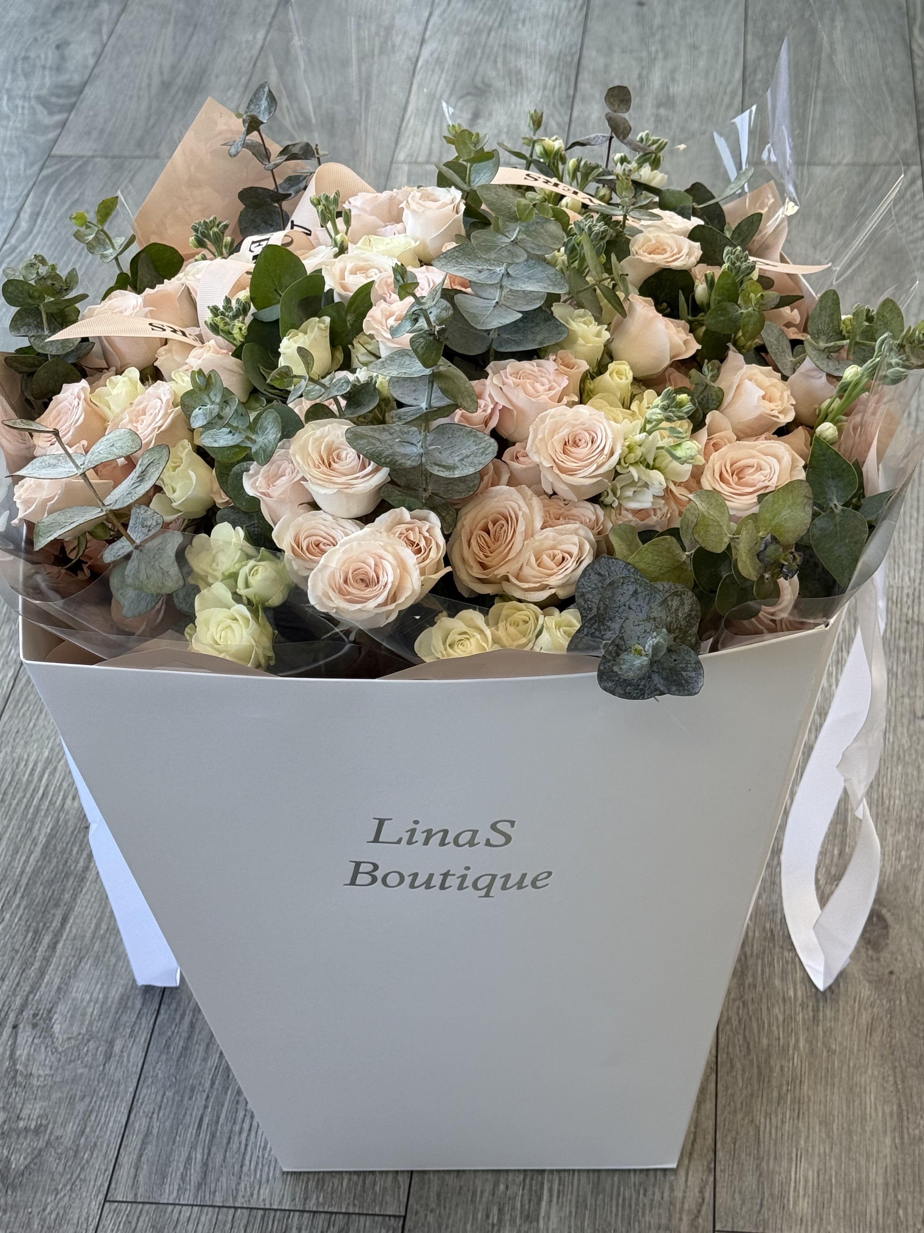 Bouquet of pale pink roses and eucalyptus in a white box